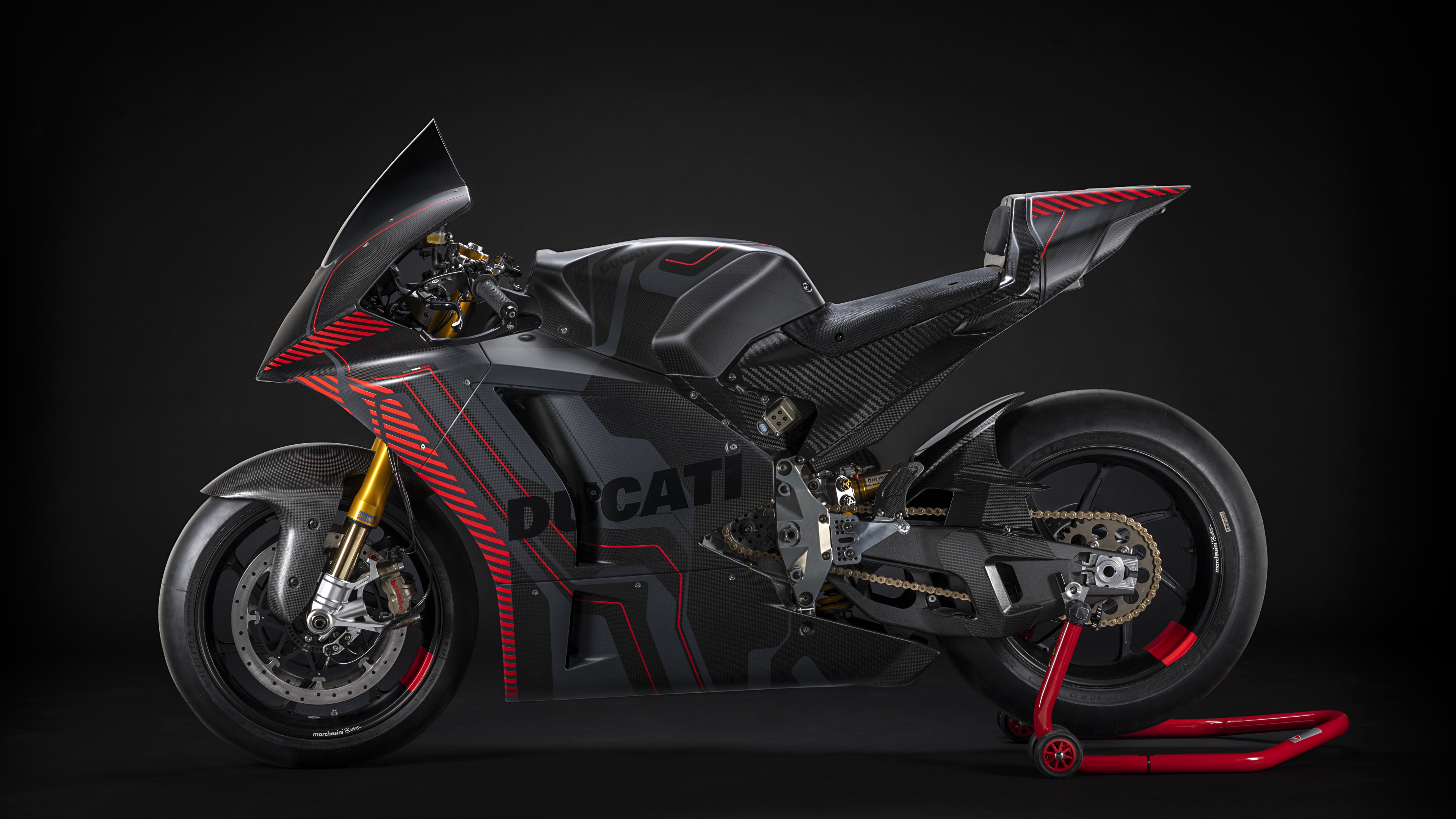A sleek Ducati V21L MotoE electric prototype racing motorcycle positioned against a dark, atmospheric background.