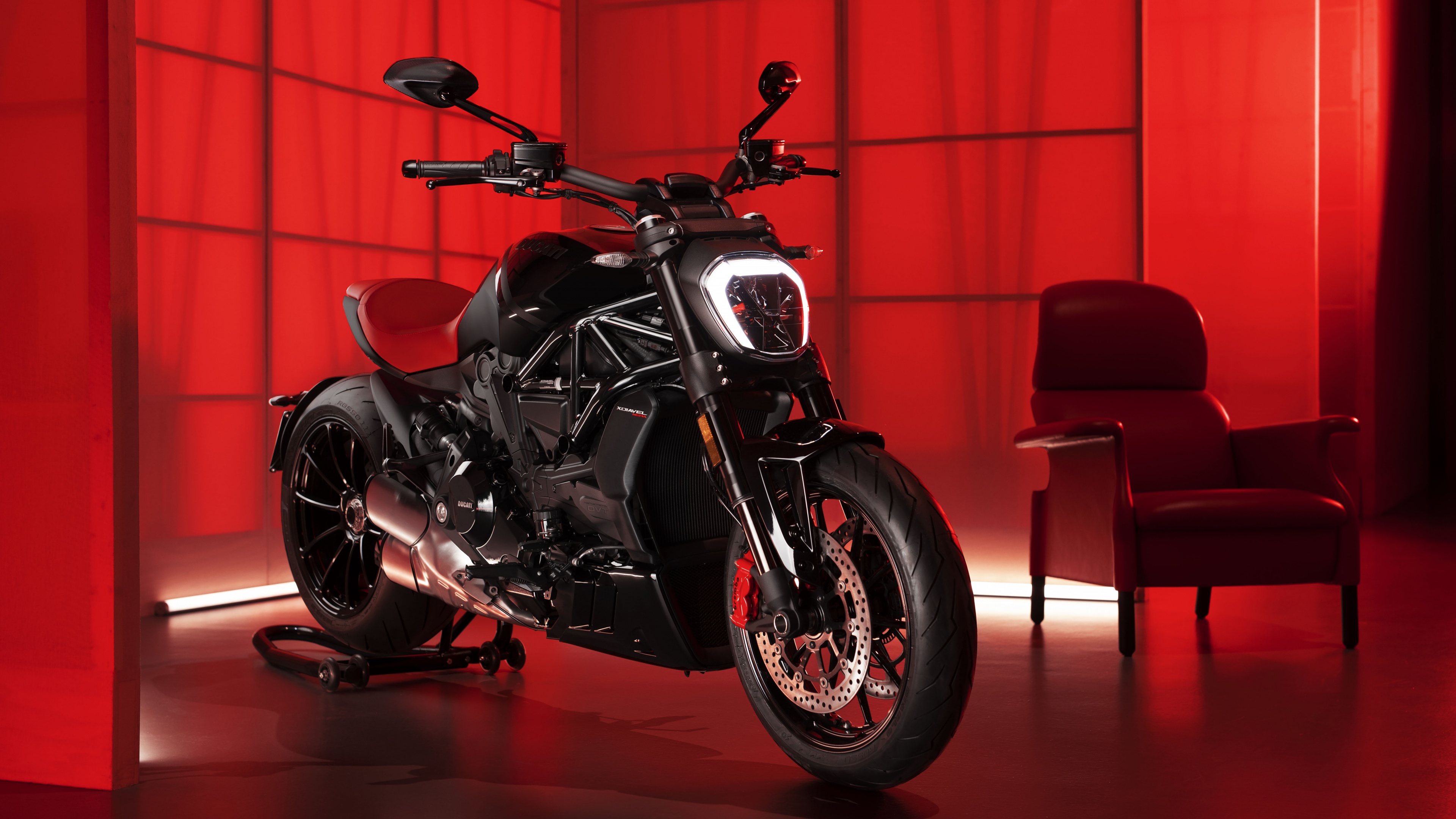 A detailed 8K view of a black Ducati XDiavel Nera sports cruiser motorcycle against a vibrant red background.