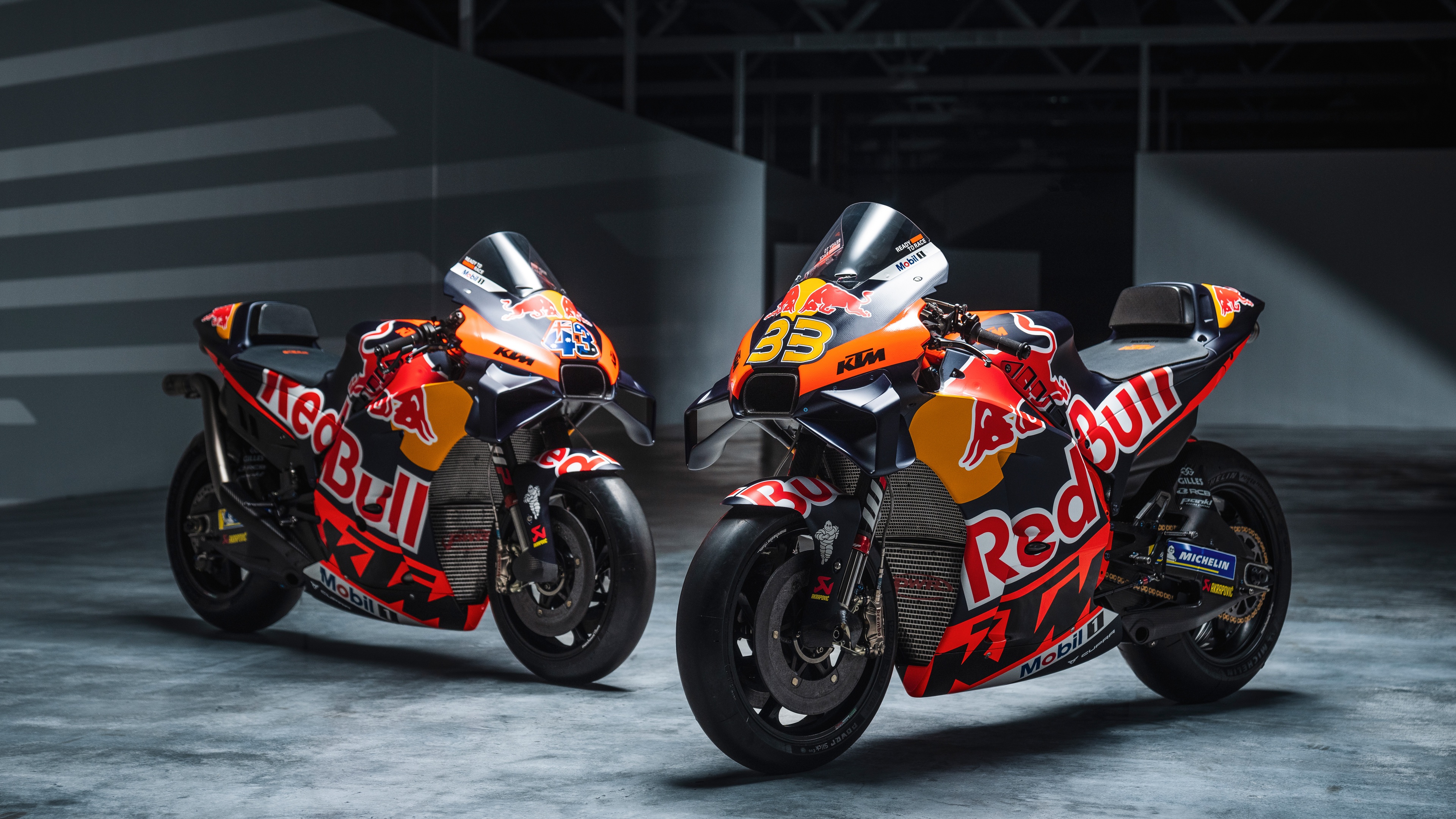 High-speed MotoGP racing bikes leaning into a corner on a professional racetrack.