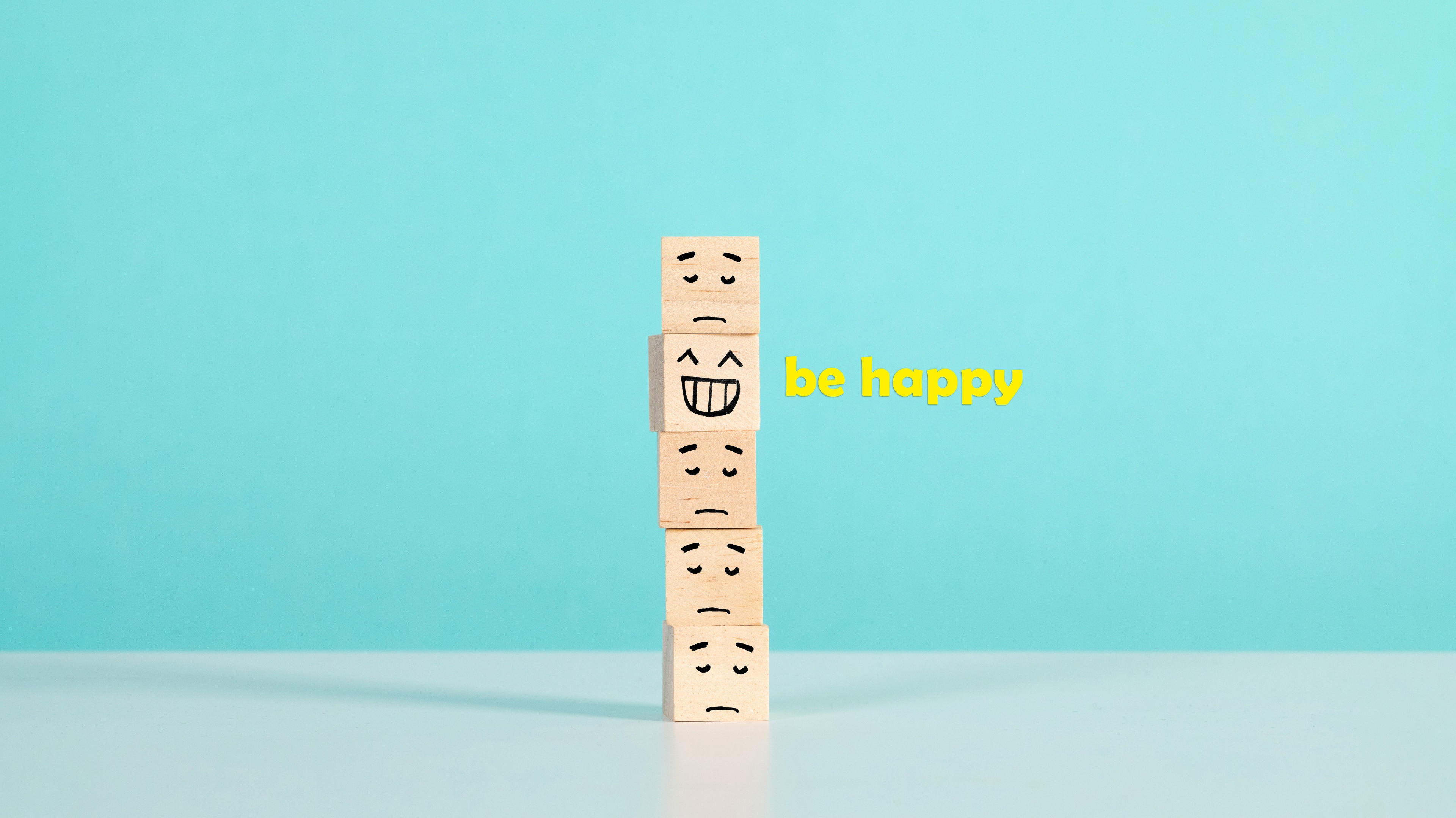 Two emoticons displaying contrasting expressions of sadness and joy on a bright cyan background.