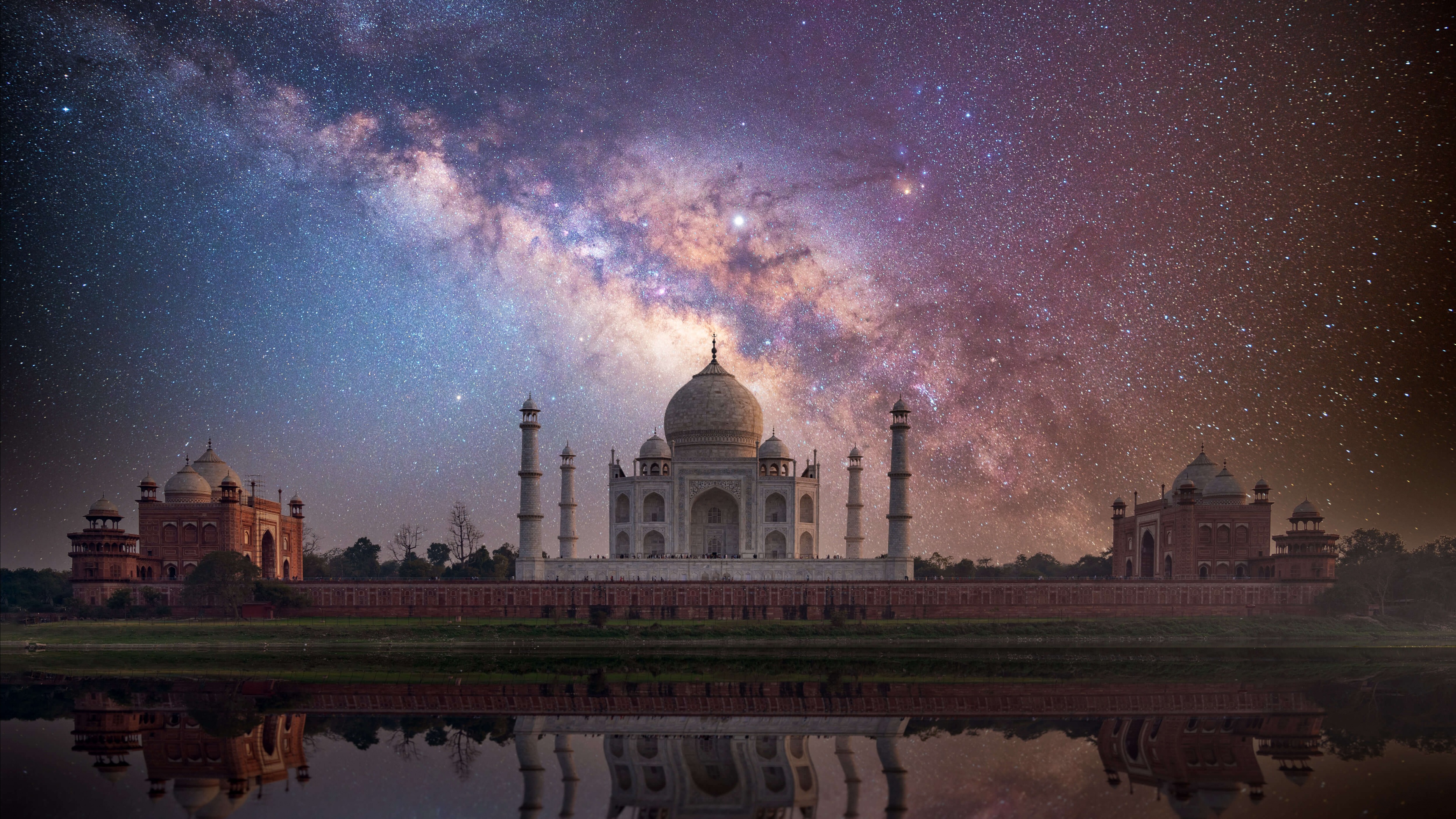 The Taj Mahal reflected in water under a starry Milky Way night sky in Agra, India.
