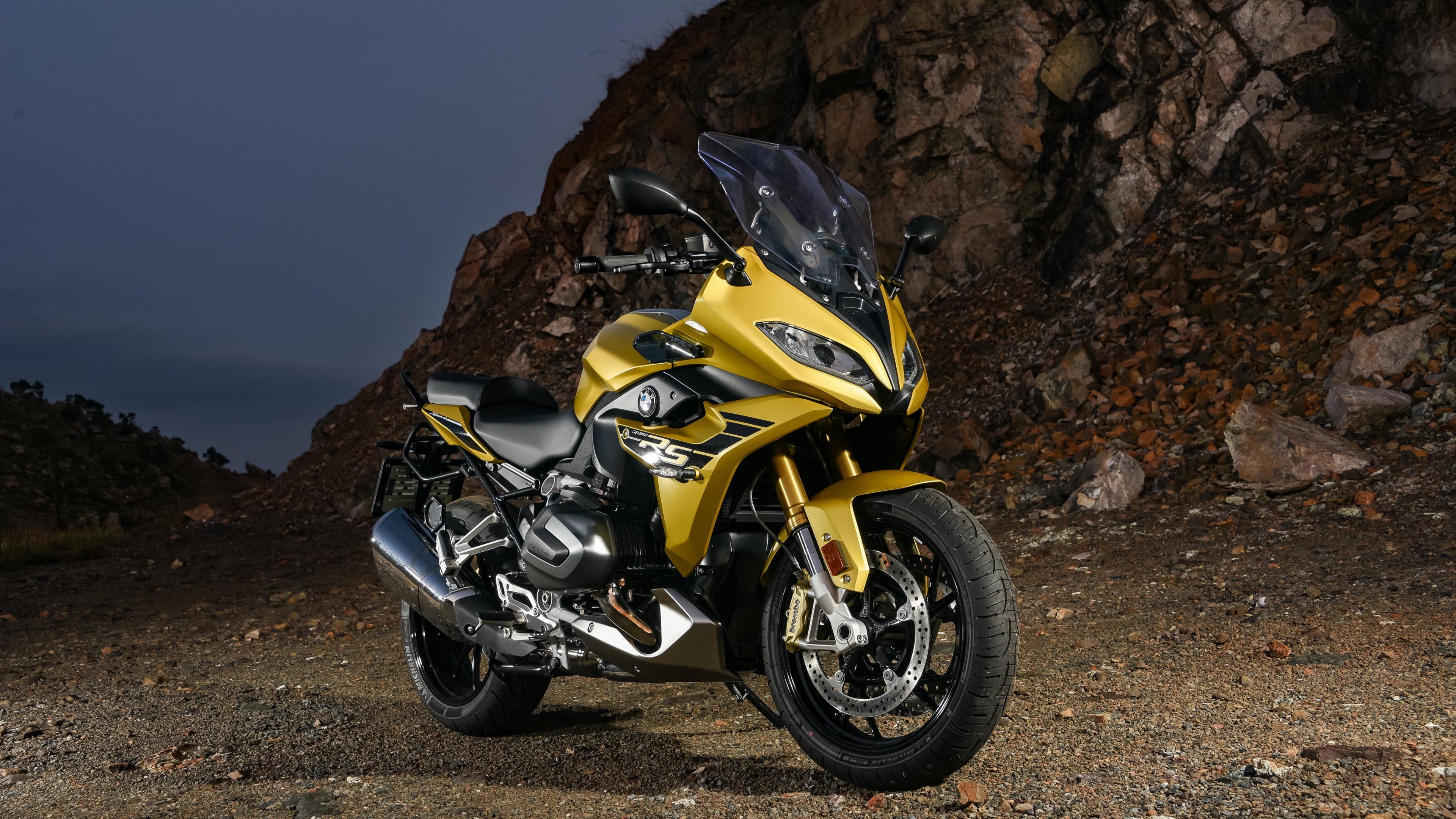 A group of sleek, multi-colored sports motorcycles parked on a professional racing circuit.