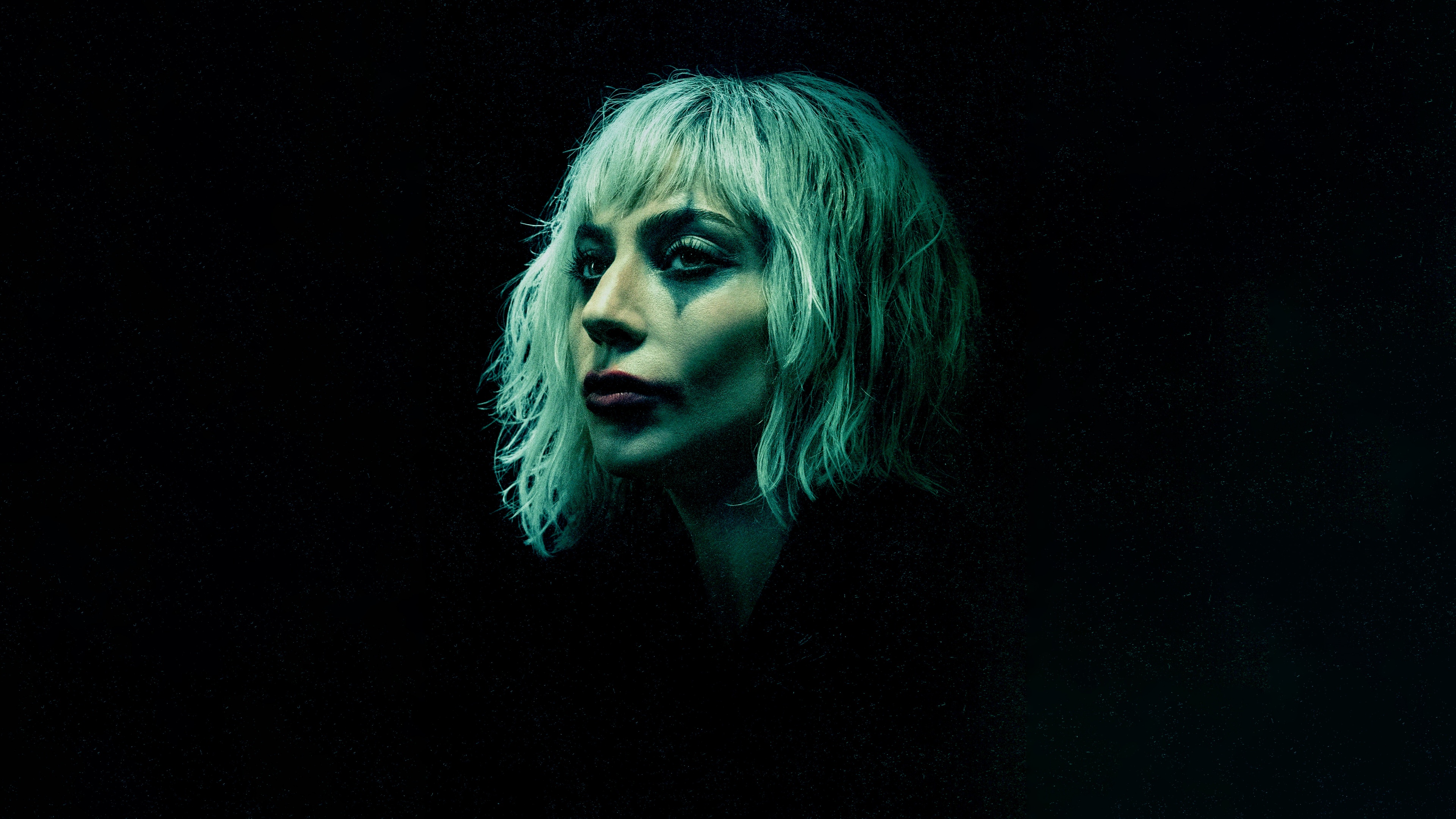 Cinematic close-up of Lady Gaga as Harley Quinn from the movie Joker: Folie à Deux against a dark background.