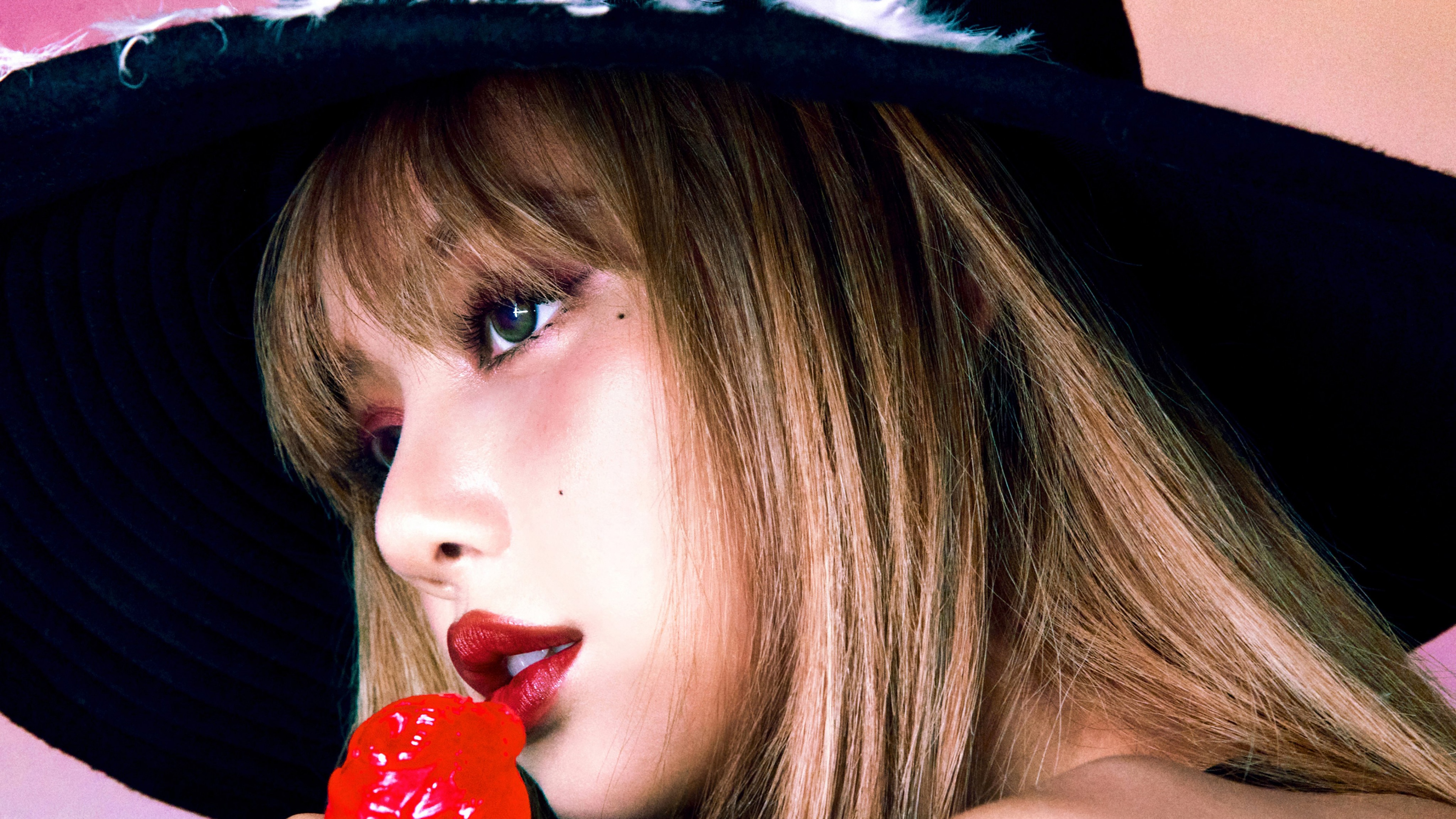 A close-up, high-fashion portrait of Lisa from BLACKPINK featuring bold lipstick and elegant styling.