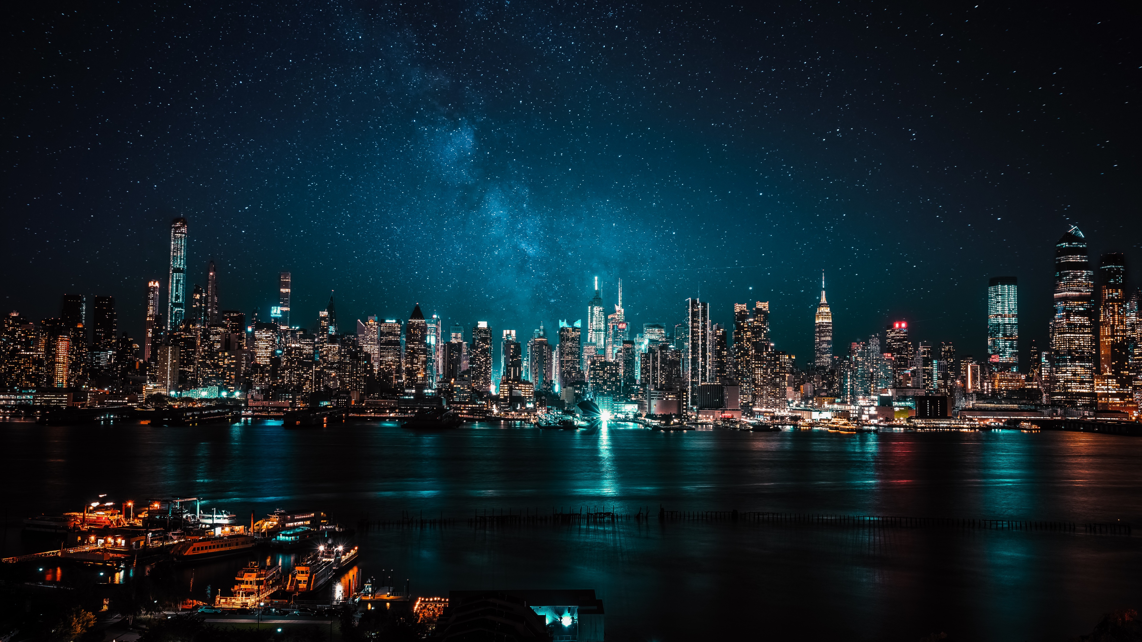 A panoramic view of a glowing night city with bright lights, reflections on wet streets, and a clear starry sky above.