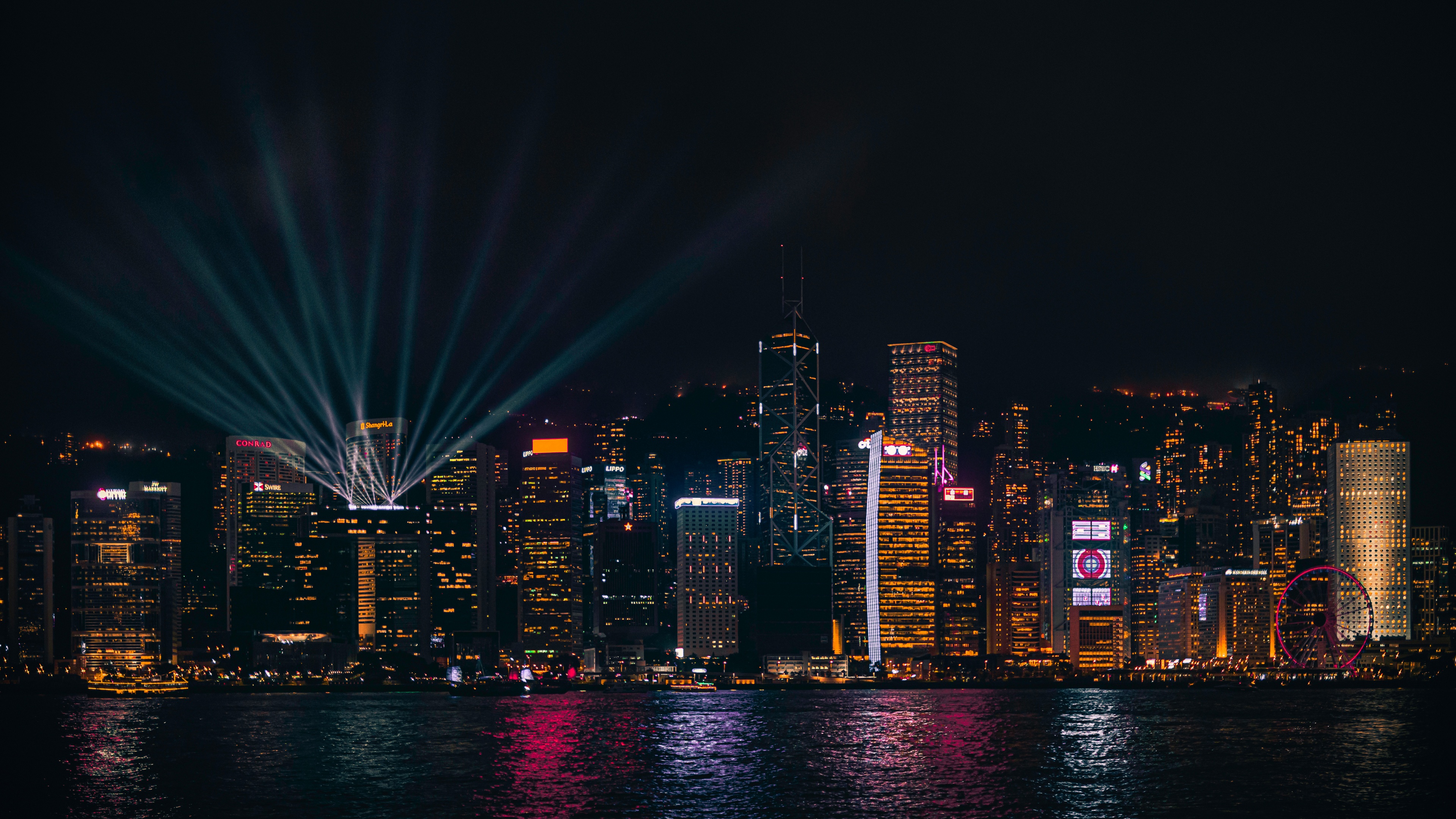 A panoramic nighttime view of Hong Kong's neon-lit skyscrapers and their colorful reflections in the harbor.