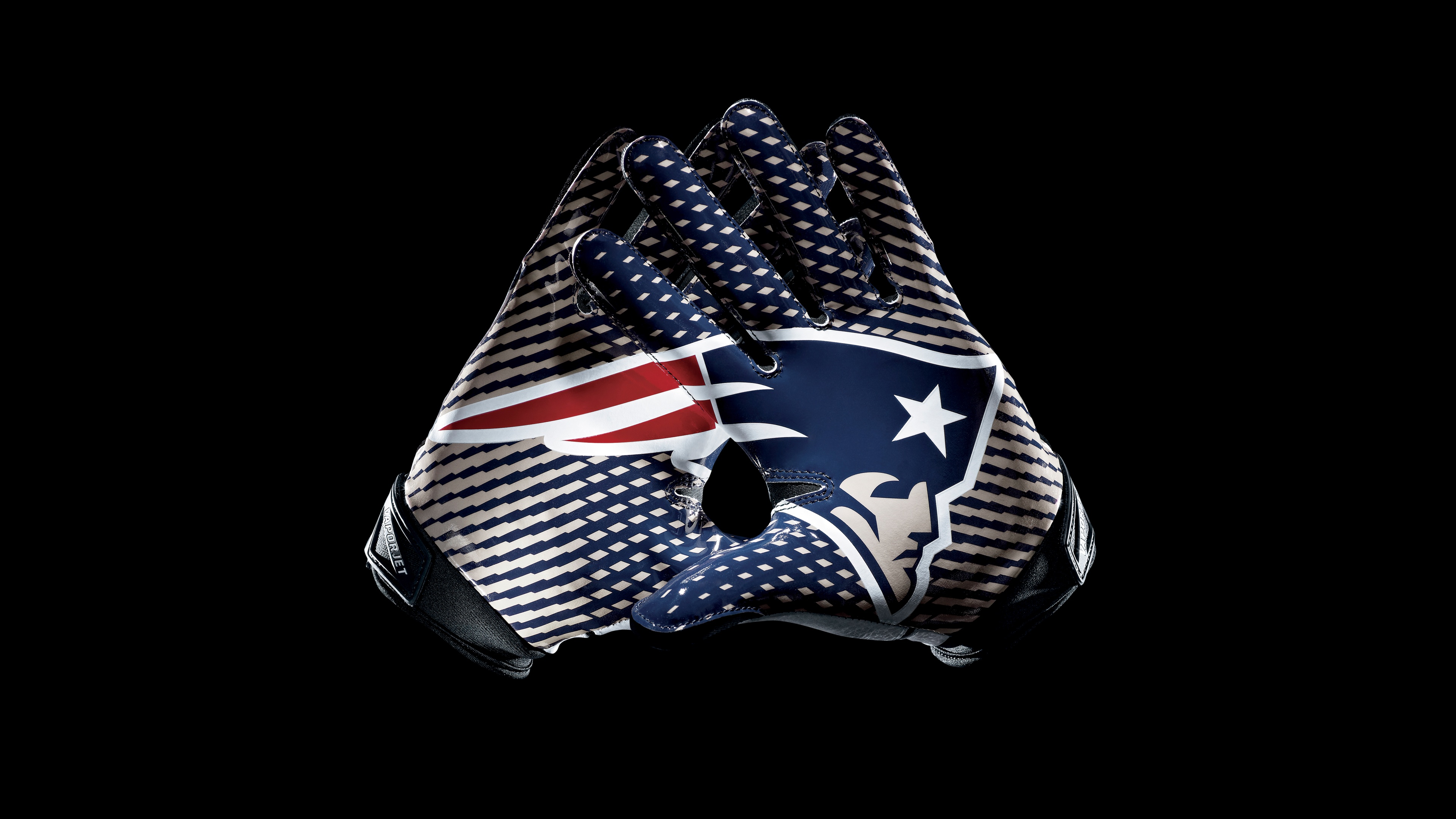Close-up of New England Patriots football gloves with team logo on a black background.