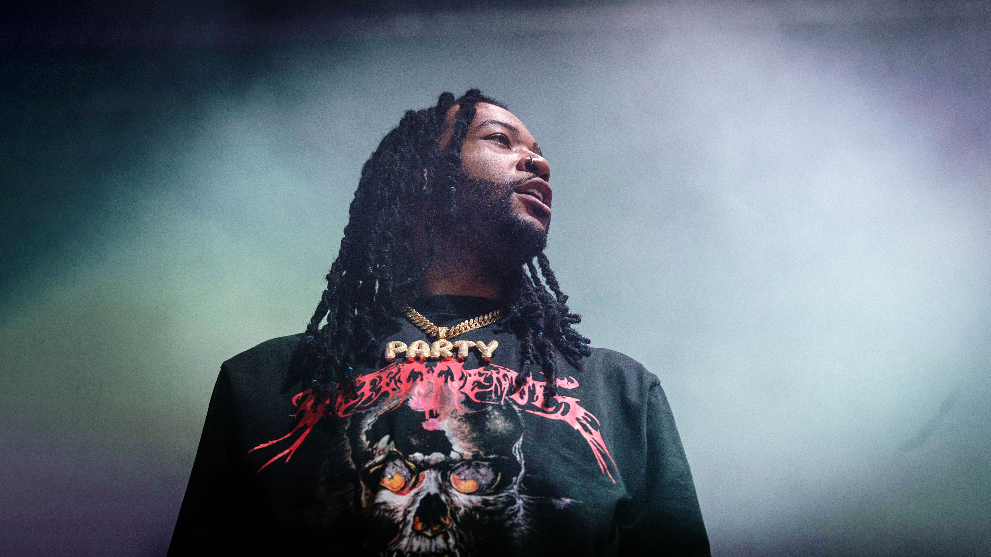 Canadian singer PartyNextDoor performing live on stage during a concert with dramatic stage lighting.