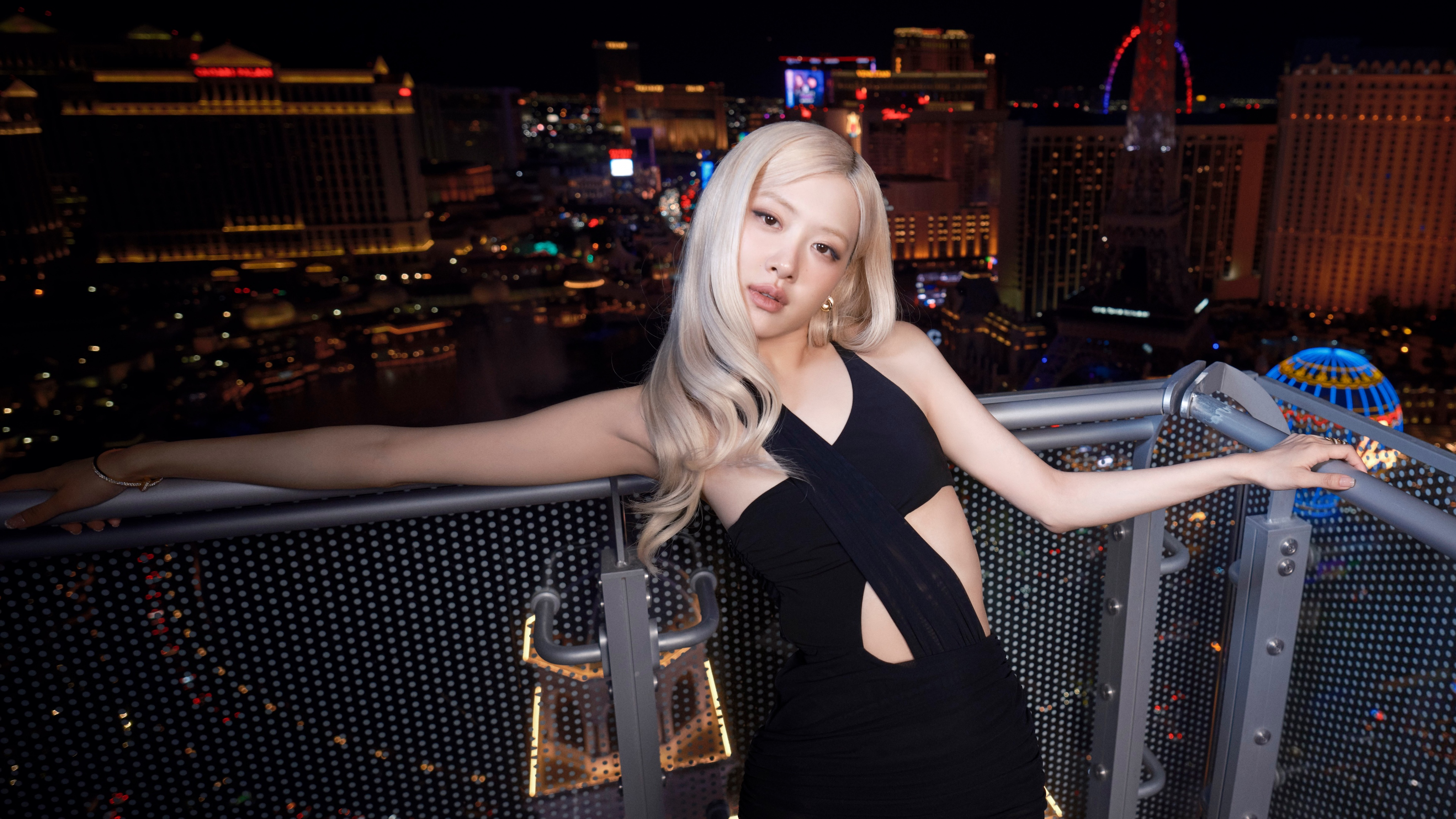 Rosé from BLACKPINK wearing a glamorous black dress against a night background