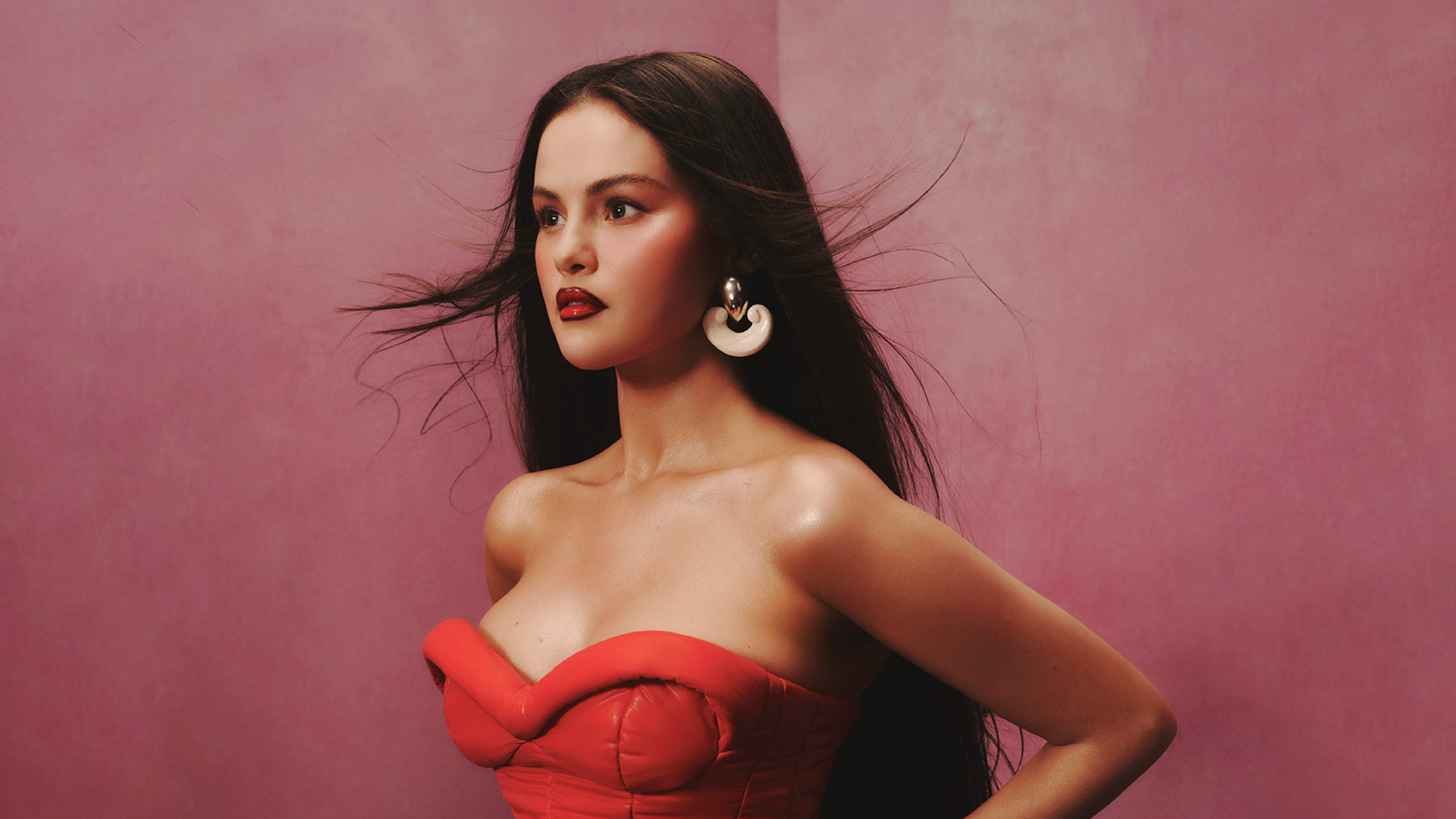 Selena Gomez posing gracefully in a luxurious red gown for an Allure magazine-inspired fashion photoshoot.