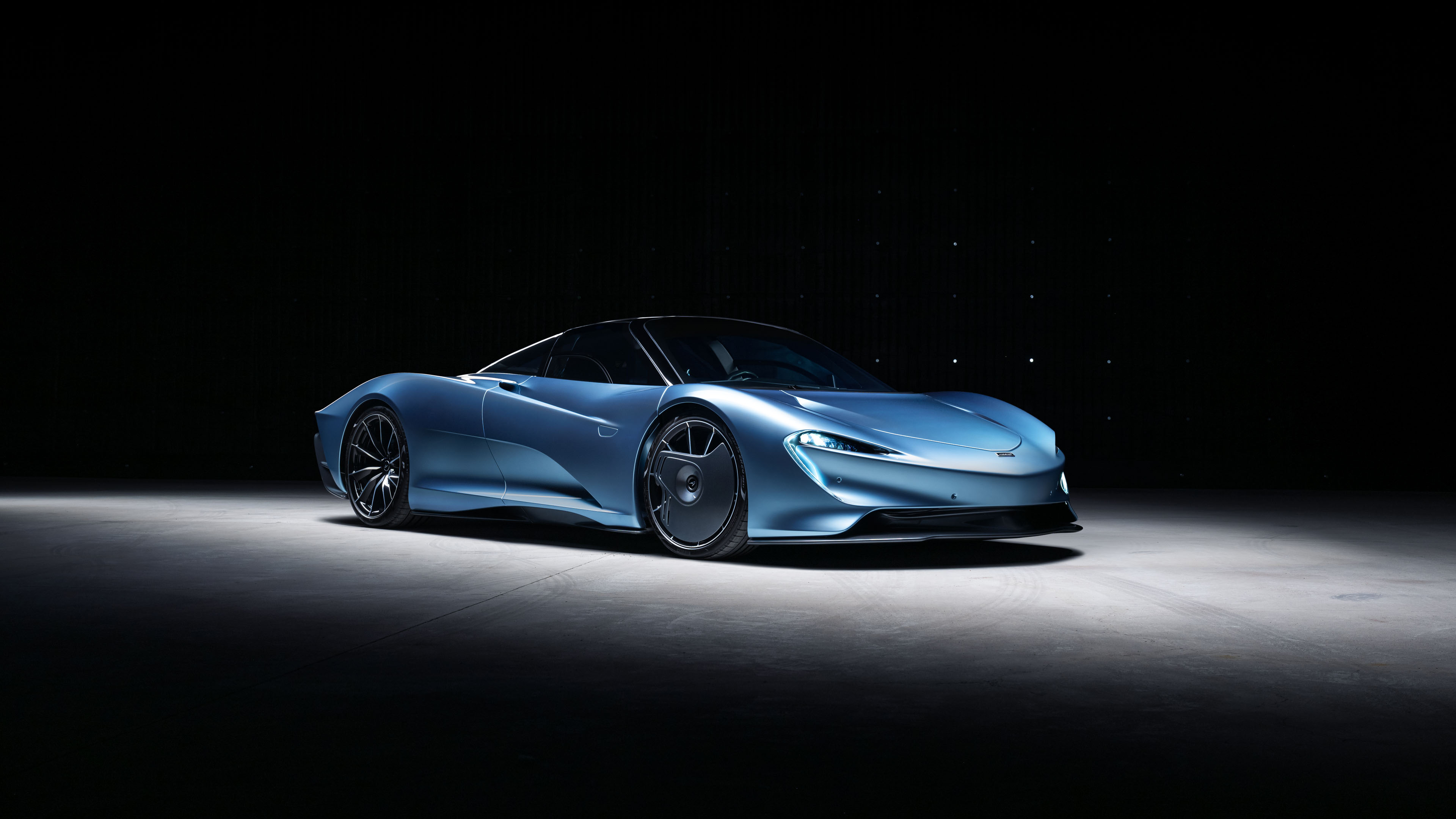 A McLaren Speedtail hybrid sports car captured in a dark, moody setting highlighting its aerodynamic shape and glossy finish.