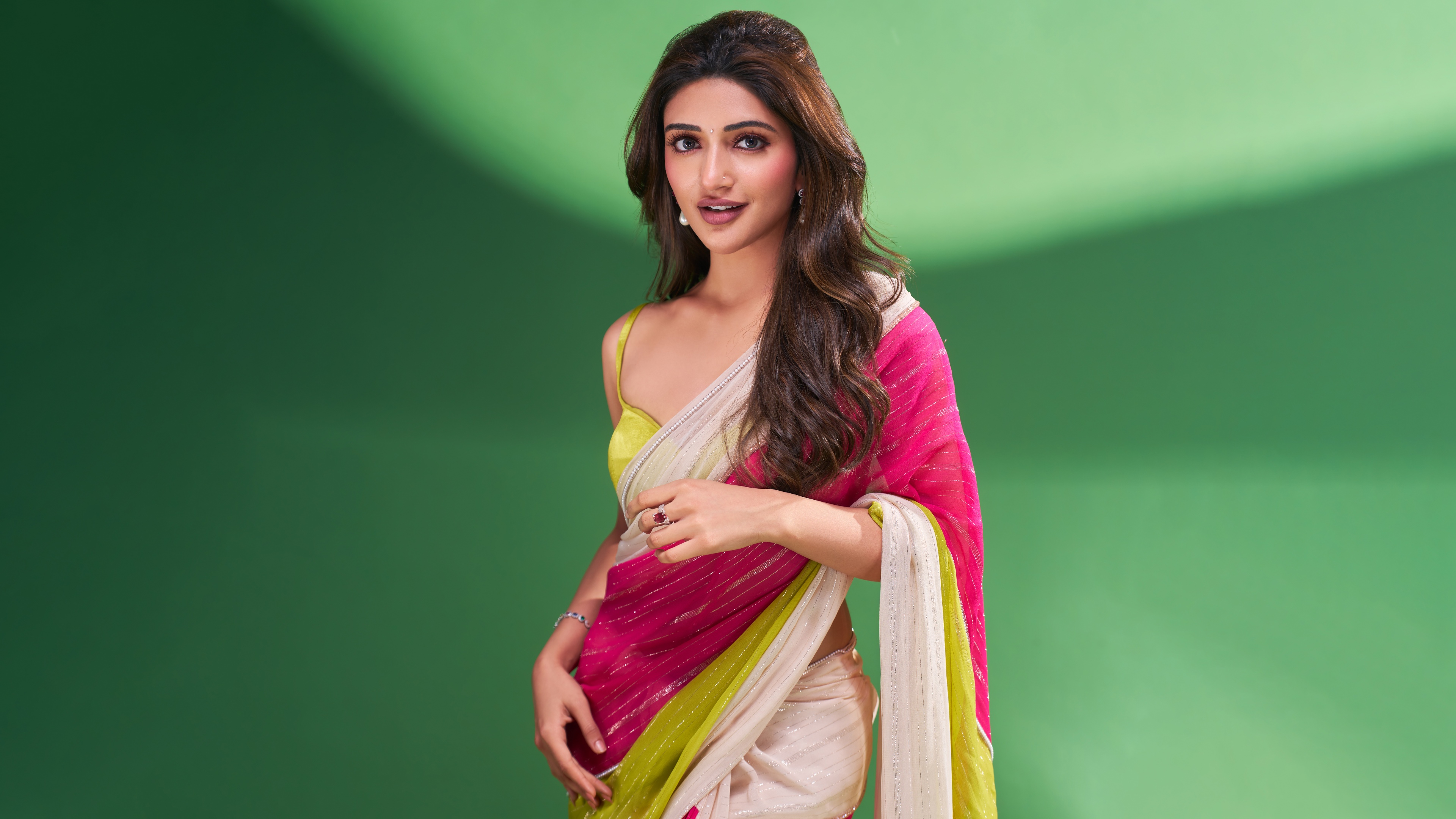 A high-resolution close-up of Indian actress Sreeleela dressed in a traditional saree with a vibrant green backdrop.