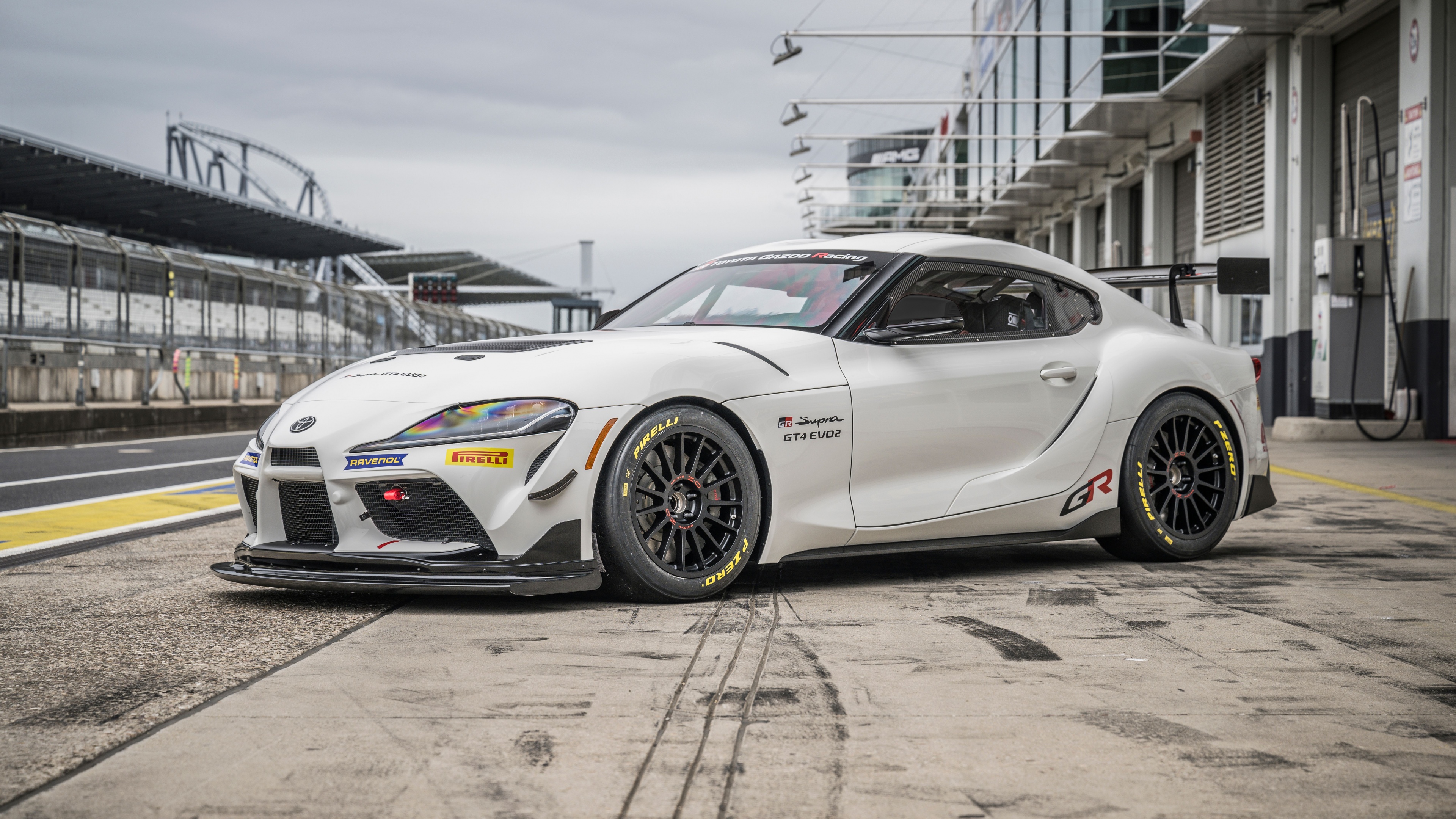 A detailed prototype of the Toyota GR Supra GT4 racing through a curve on a professional circuit track.