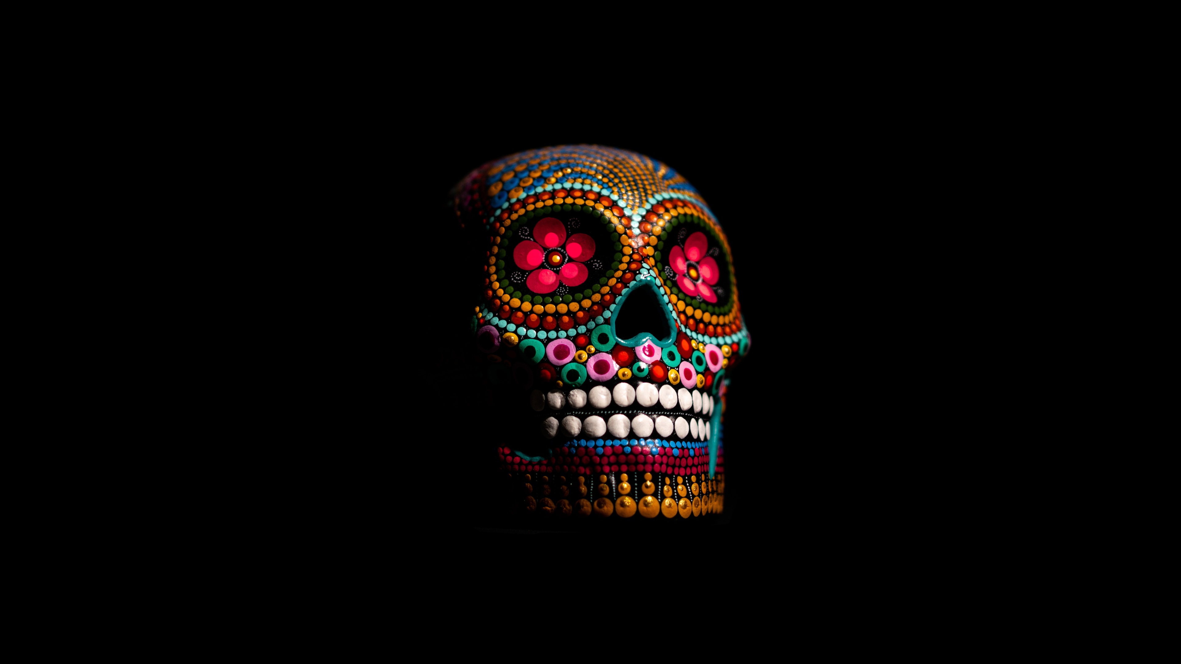A highly detailed skull featuring a spectrum of vibrant, multicolored patterns set against a dark black background.