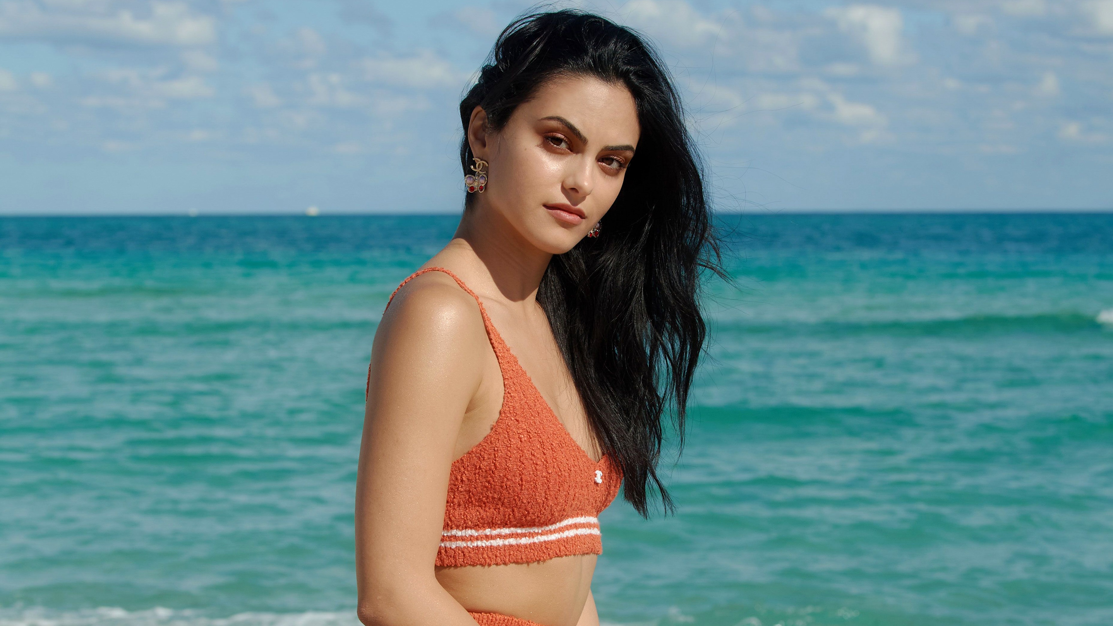 Camila Mendes posing elegantly on a tropical beach during an Elle Magazine editorial photoshoot.