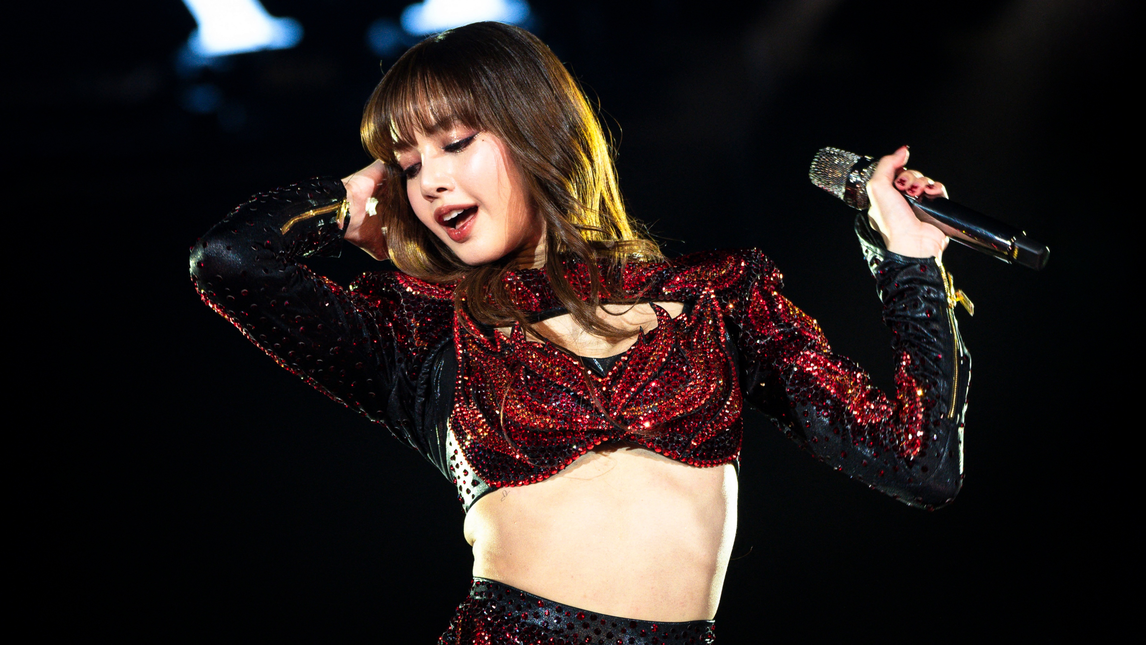 Lisa from Blackpink singing and dancing on stage during a live concert performance.