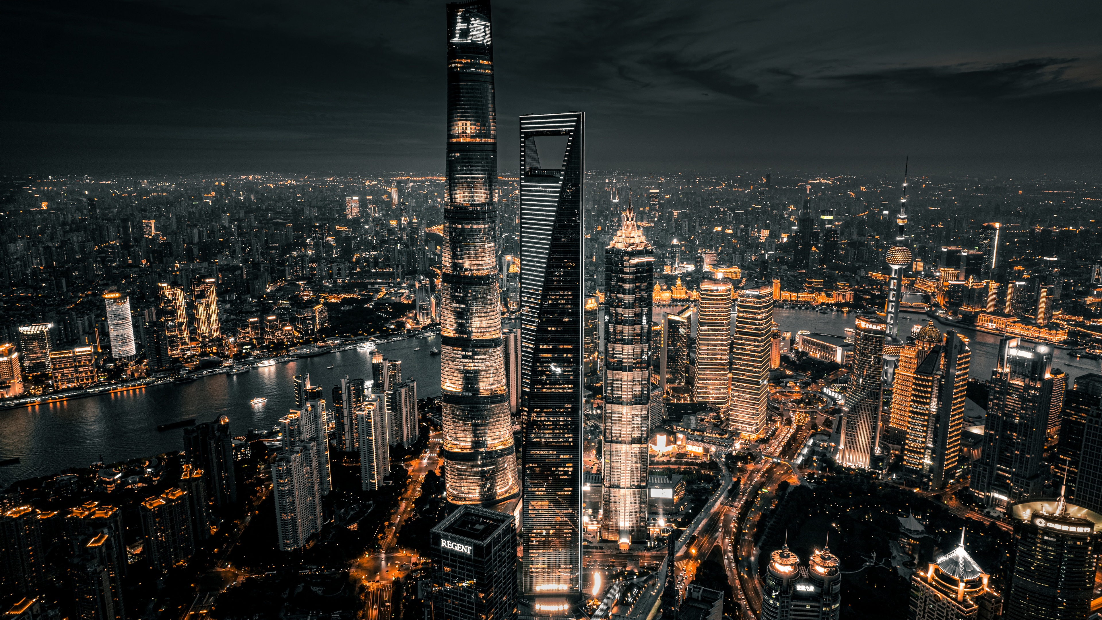 Aerial view of Shanghai skyscrapers at night with glowing city lights and a dark aesthetic.