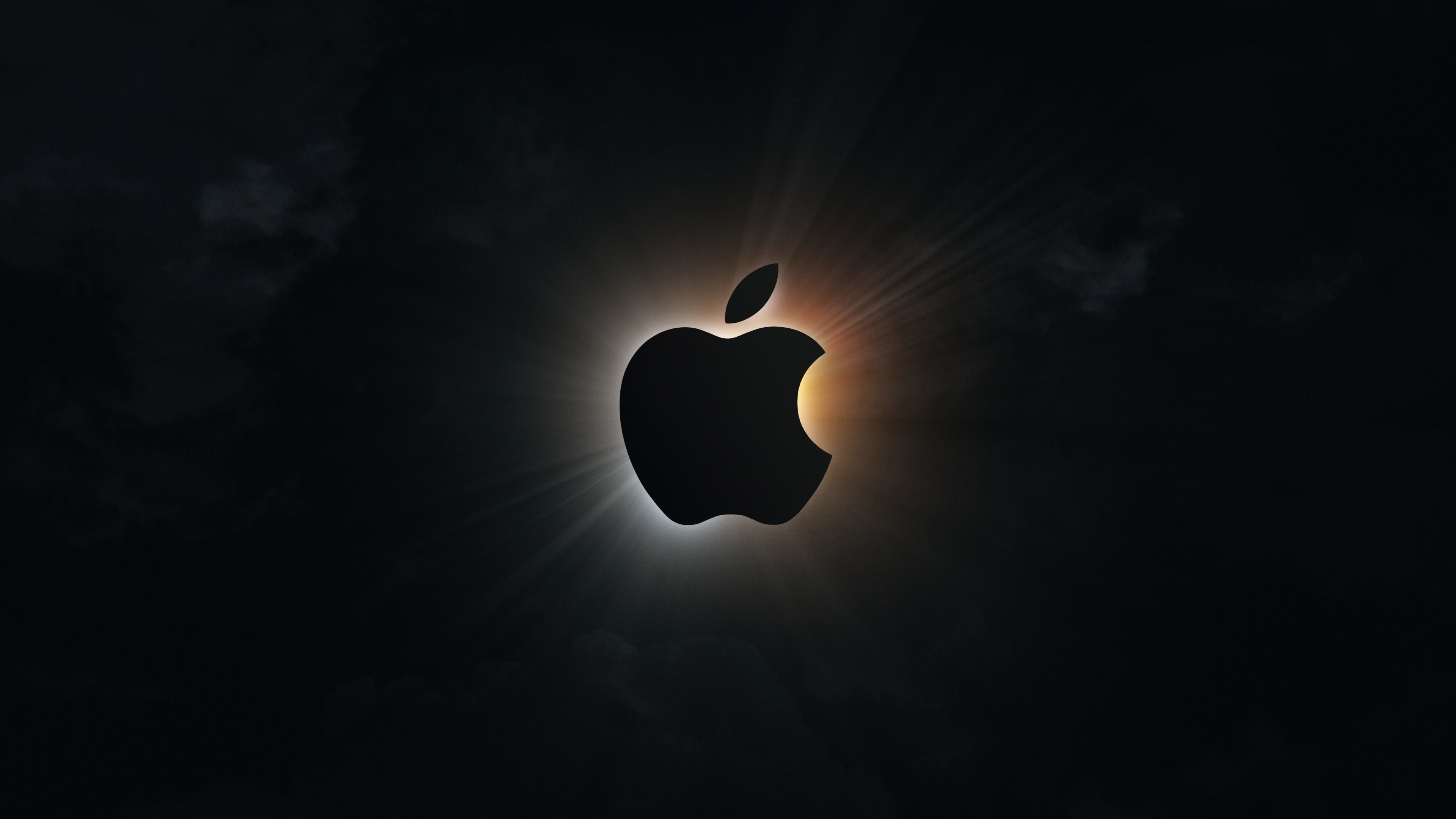 A silhouette of the Apple logo styled like a solar eclipse with a glowing ring on a dark background.