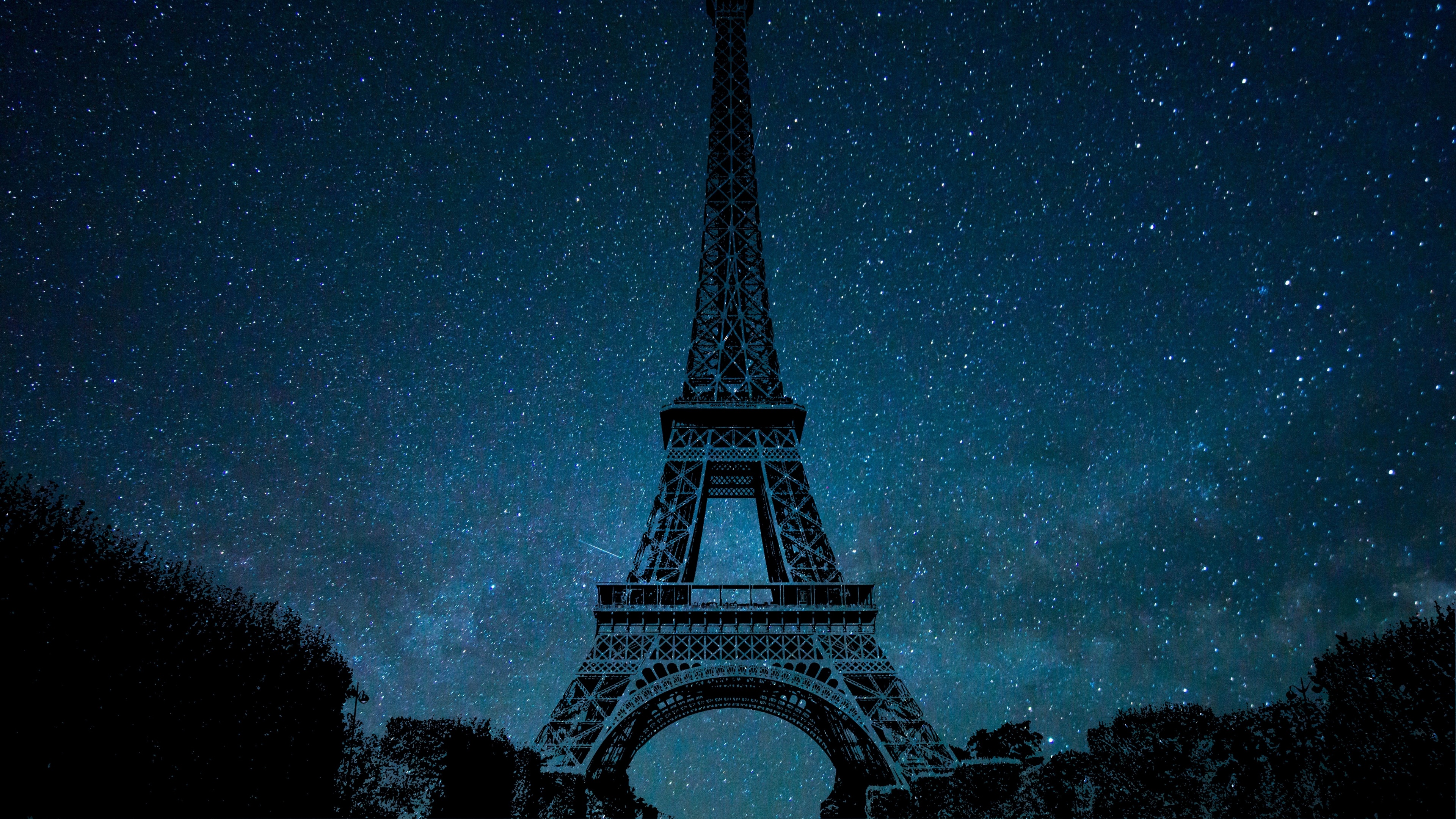 The silhouette of the Eiffel Tower in Paris, France, set against a vibrant blue night sky filled with stars.