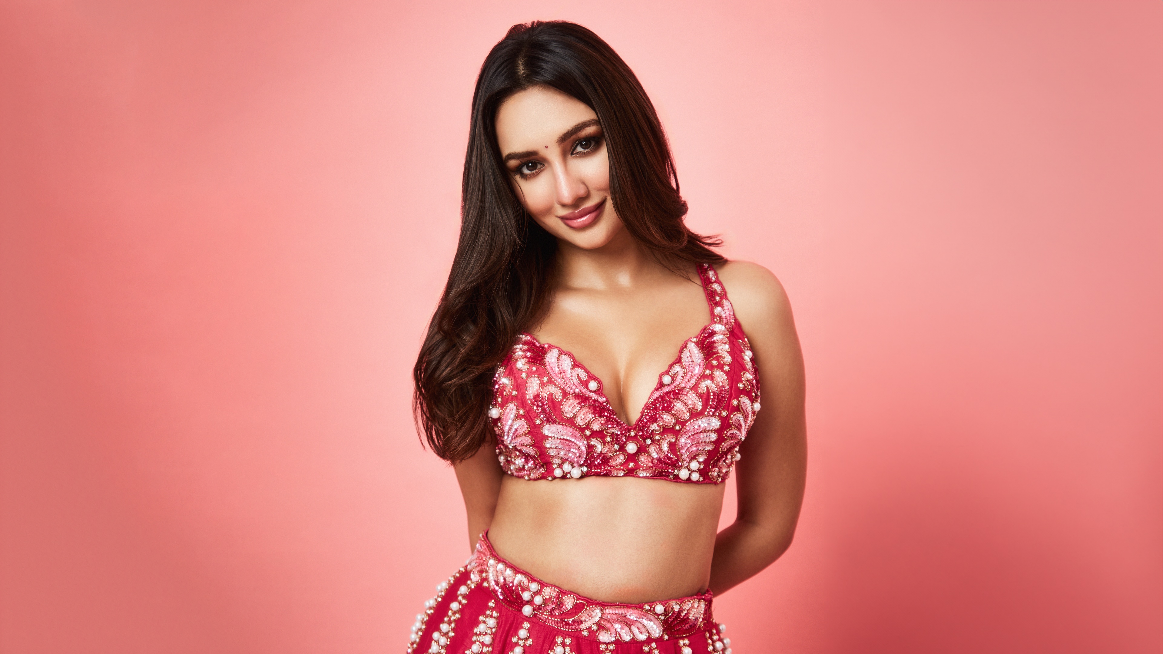 A high-resolution portrait of a beautiful Indian actress wearing a soft pastel pink ensemble.