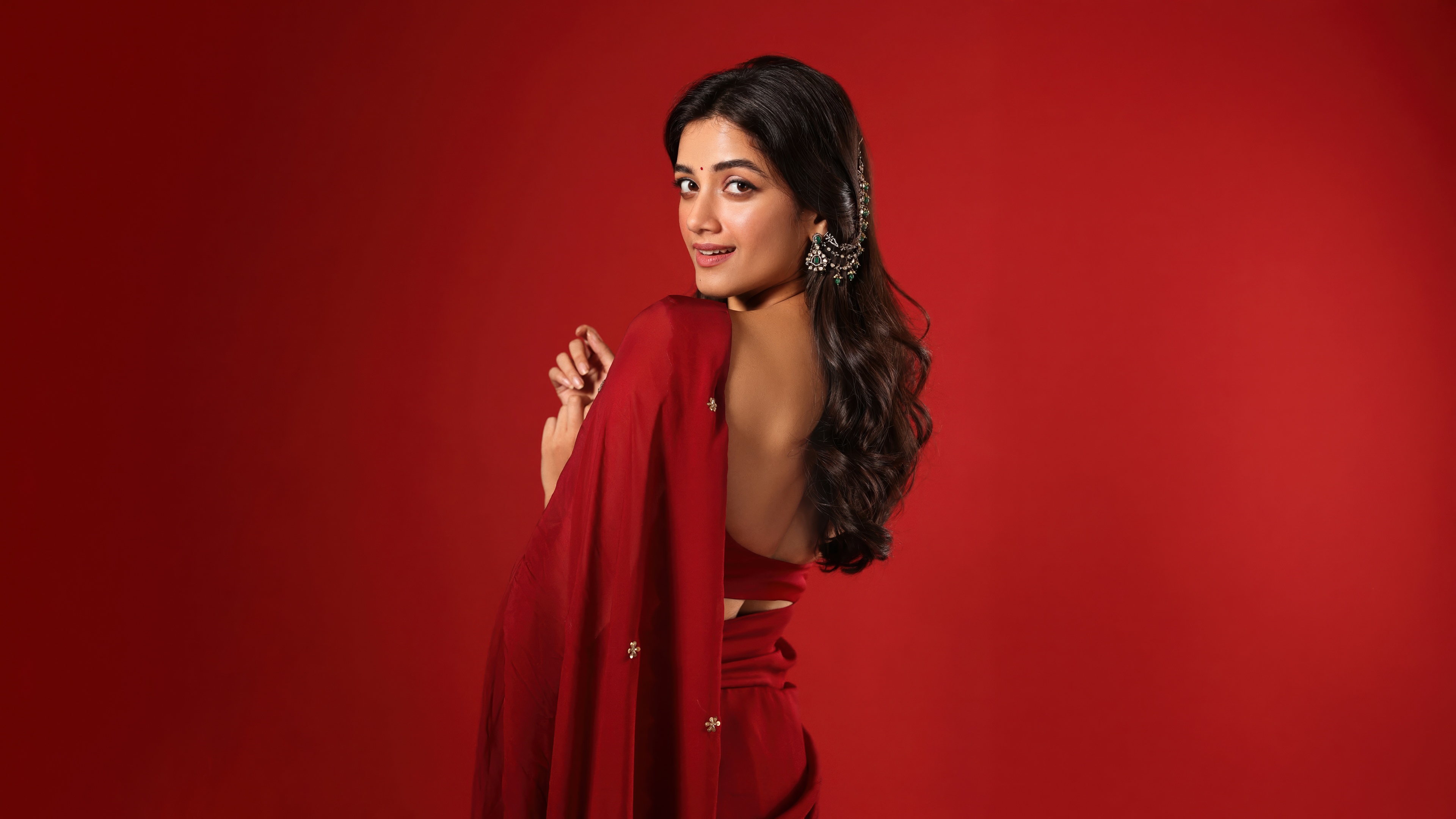 Indian actress Bhagyashri Borse posing in a red saree with a monochromatic red aesthetic and background.