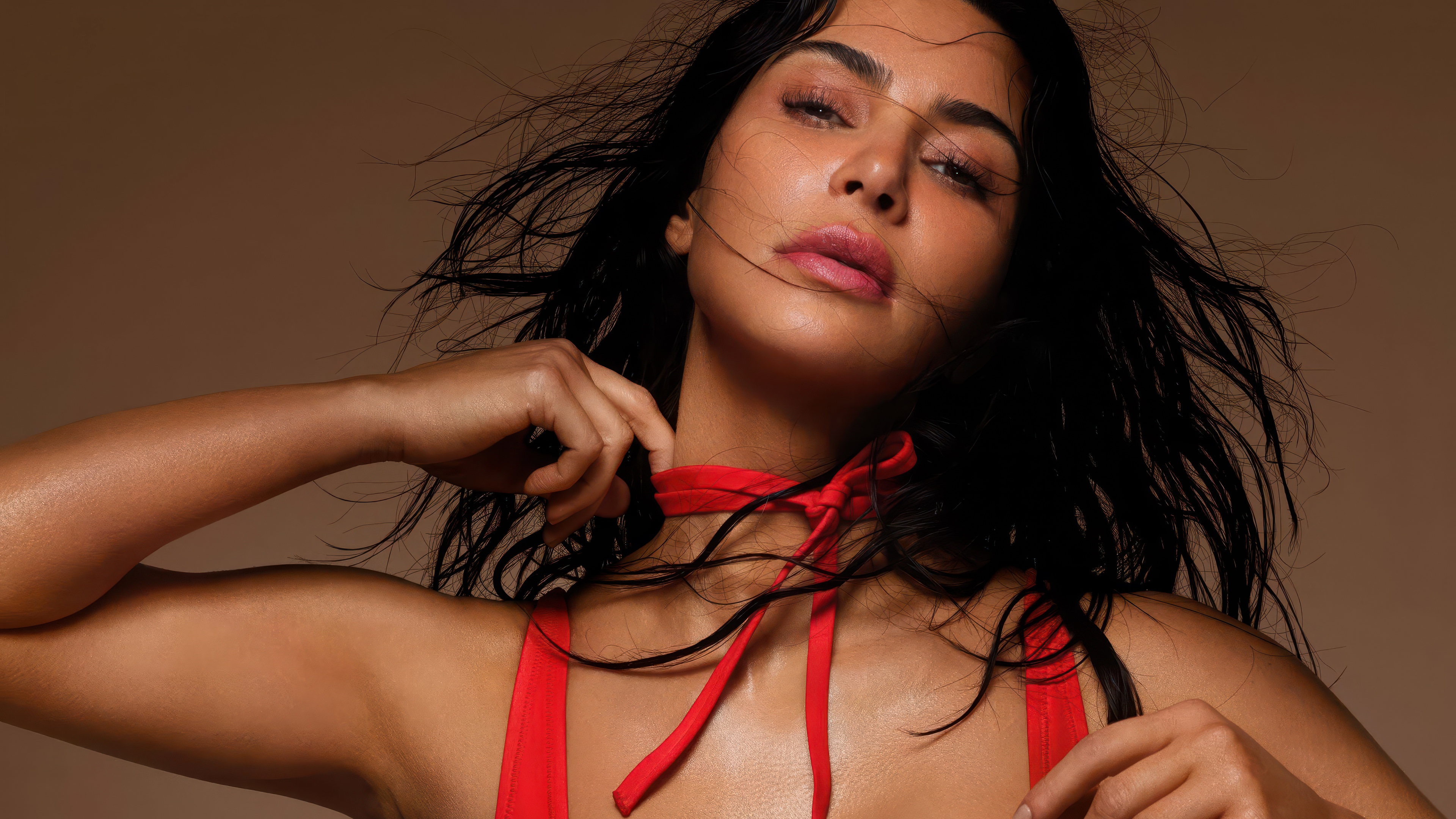 A high-resolution close-up portrait of Kim Kardashian with a bold red aesthetic and dramatic lighting.