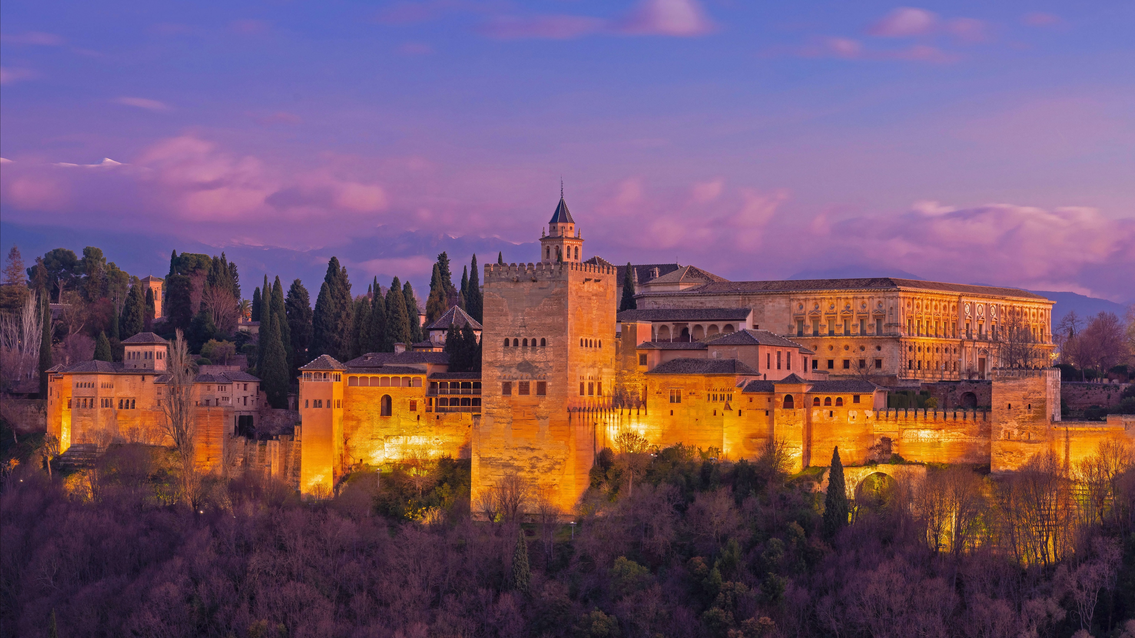 Ancient Spanish architecture and a historical landmark set against a deep purple night sky.