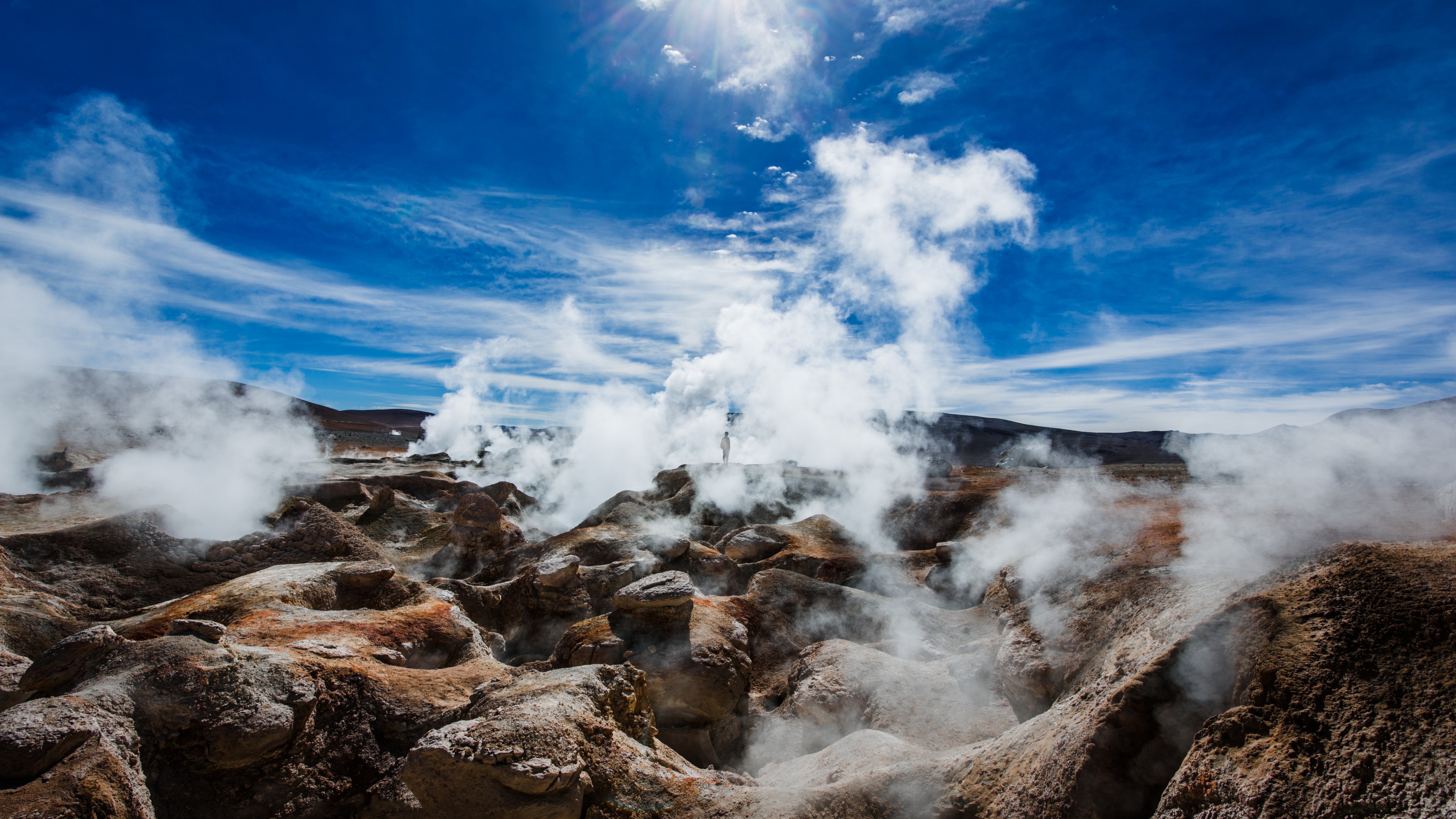 A wide-angle view of a dramatic volcanic mountain under a clear, sunny sky.