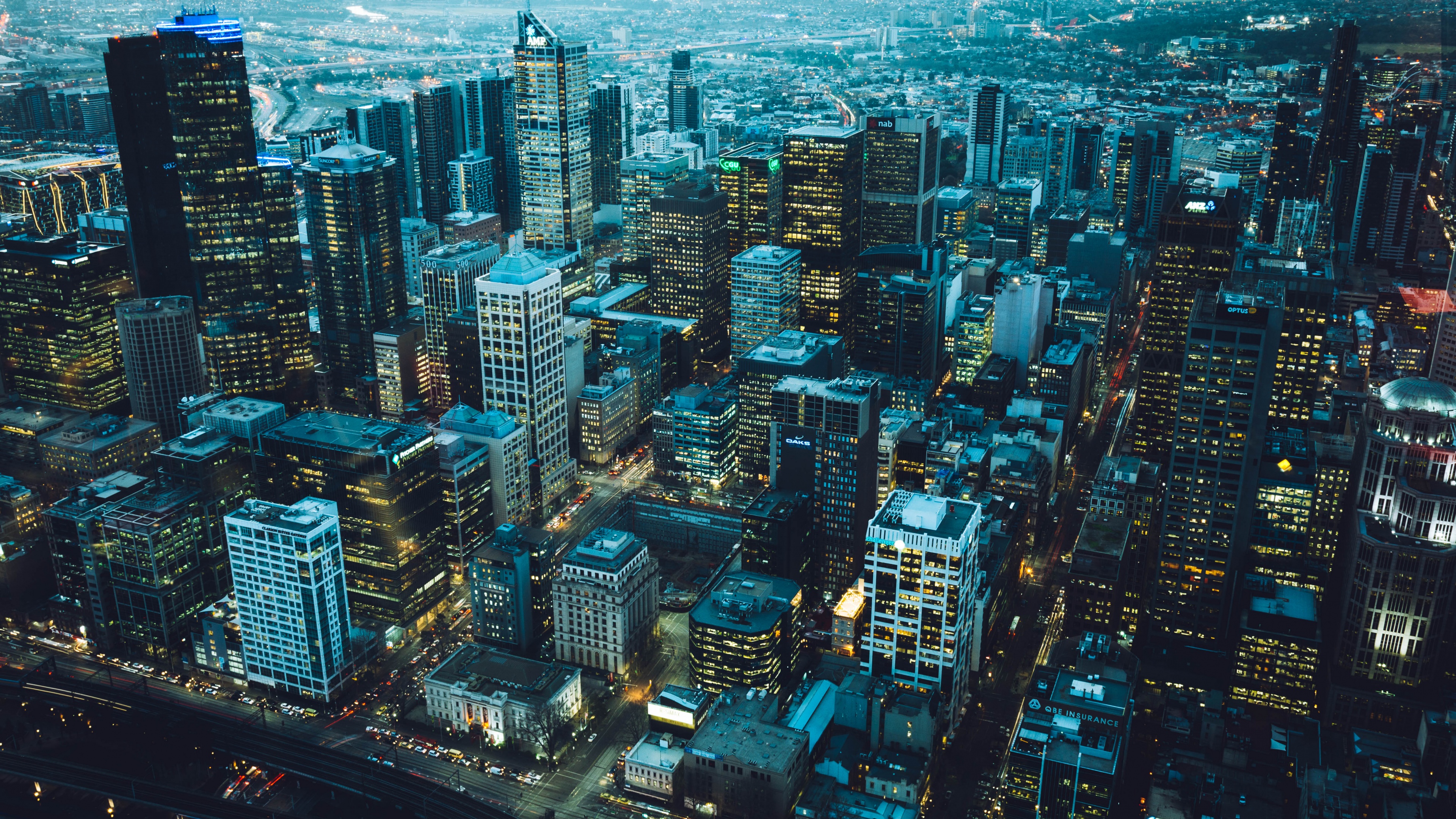 An aerial bird's eye view of a brightly lit cityscape at night featuring numerous skyscrapers and urban lights.
