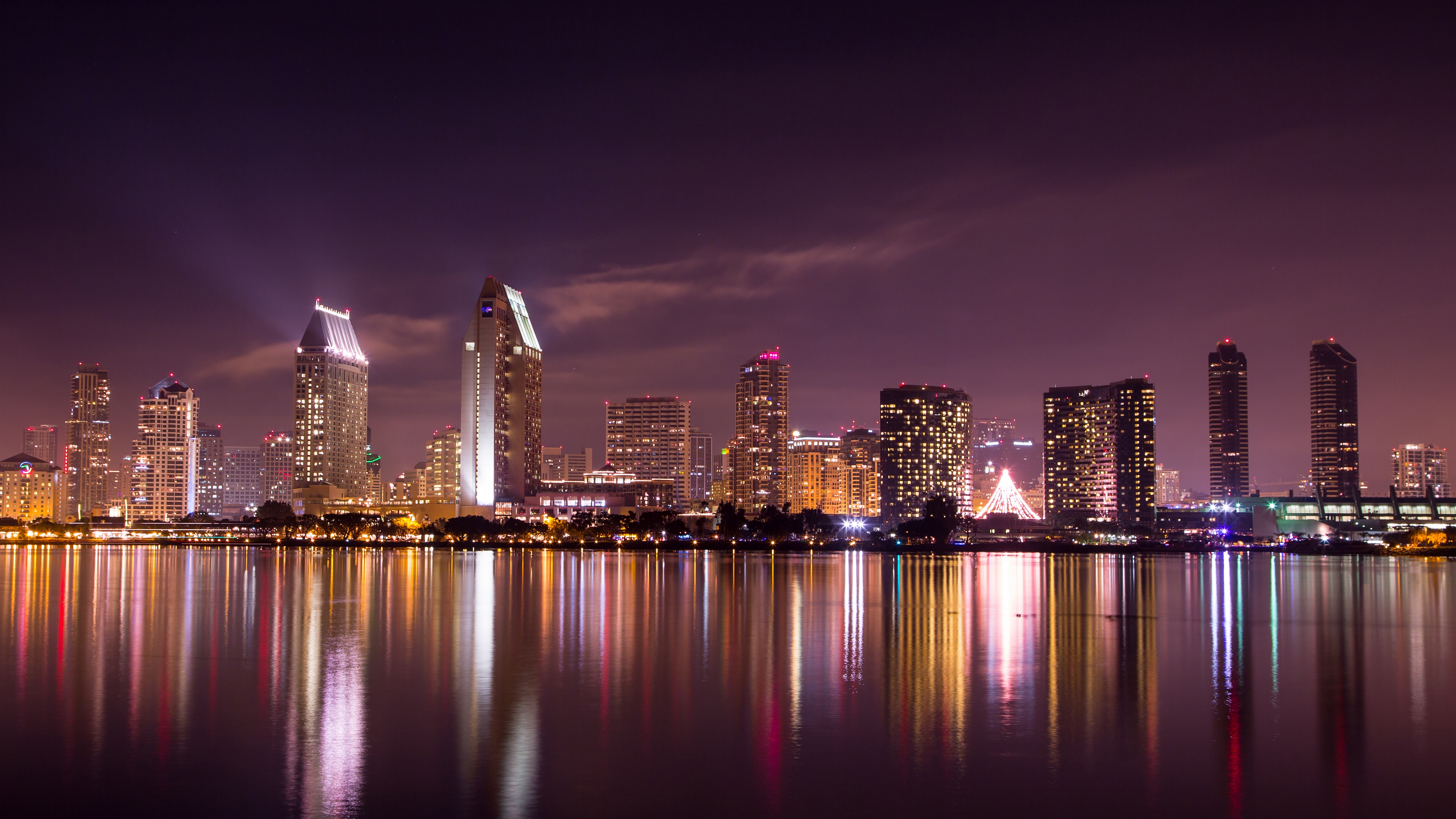 A long exposure photograph of the San Diego city skyline at night with a purple sky and glowing lights reflecting on the bay.