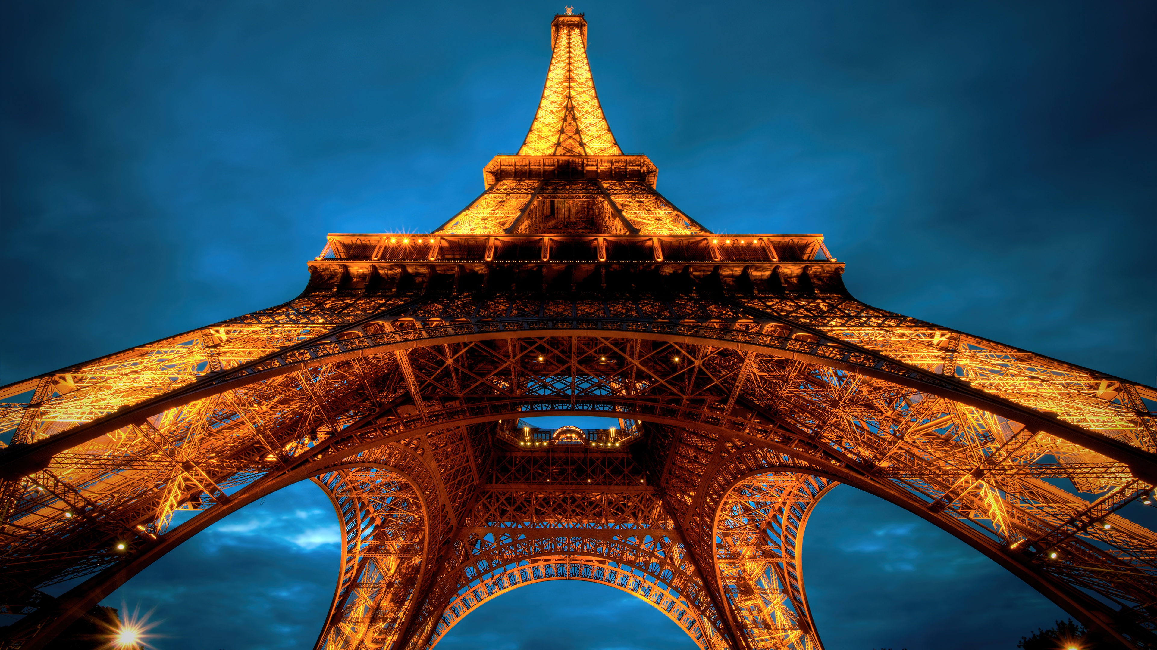 The Eiffel Tower in Paris, France, silhouetted against a cloudy sunset sky at twilight.