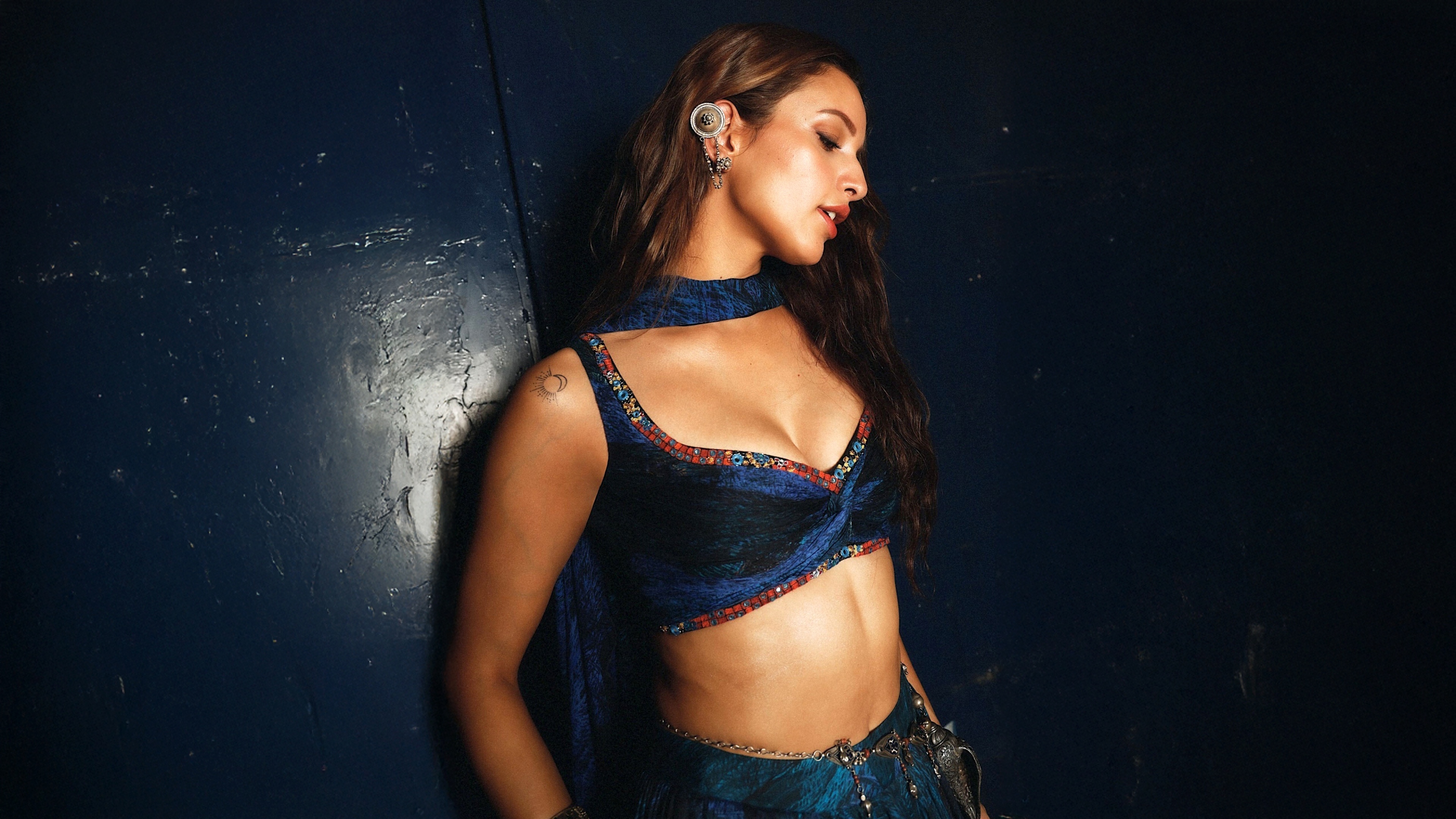 A glamorous portrait of Indian actress Tripti Dimri against a dark navy blue background.