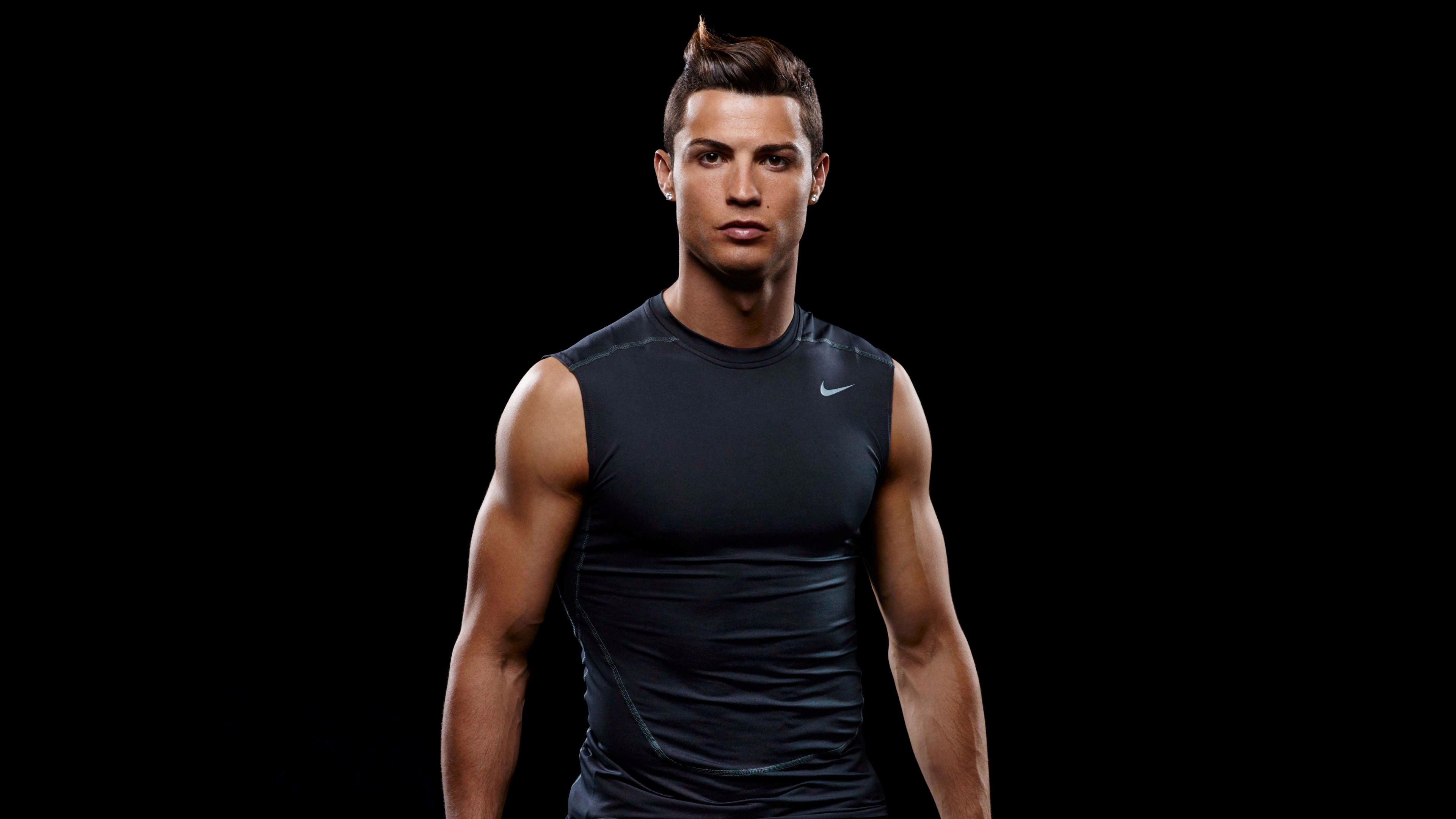 A high-definition, dramatic portrait of Cristiano Ronaldo against a pitch-black background.