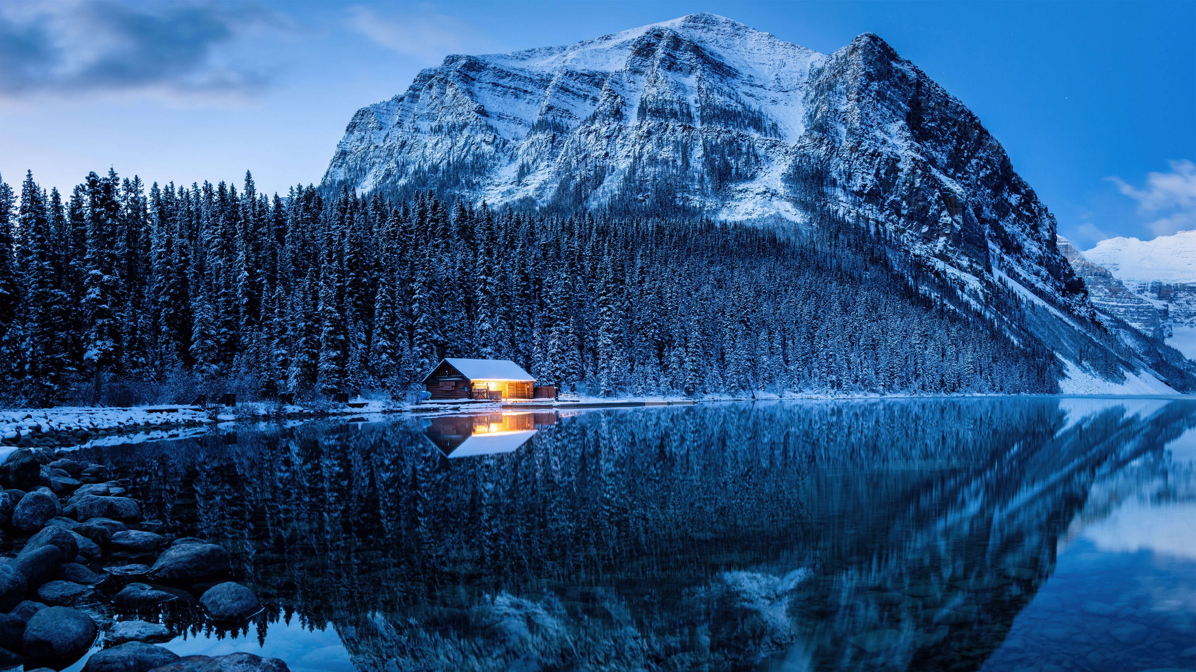 A frozen lake surrounded by snow-covered pine trees in Banff National Park, Canada, during winter.