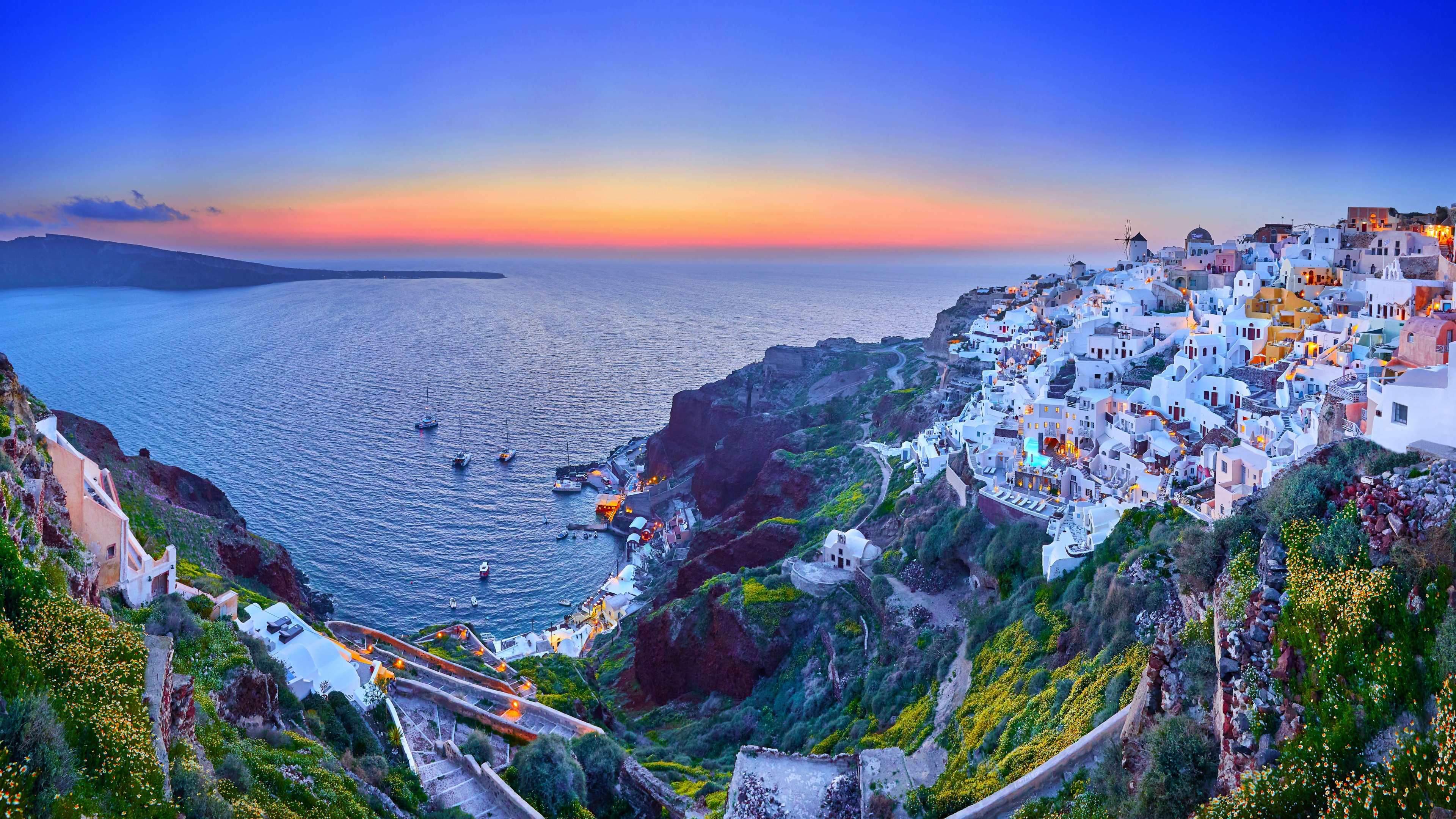A wide panoramic shot of a vibrant sunset over the Greek coast, featuring colorful dusk clouds reflecting on the sea.