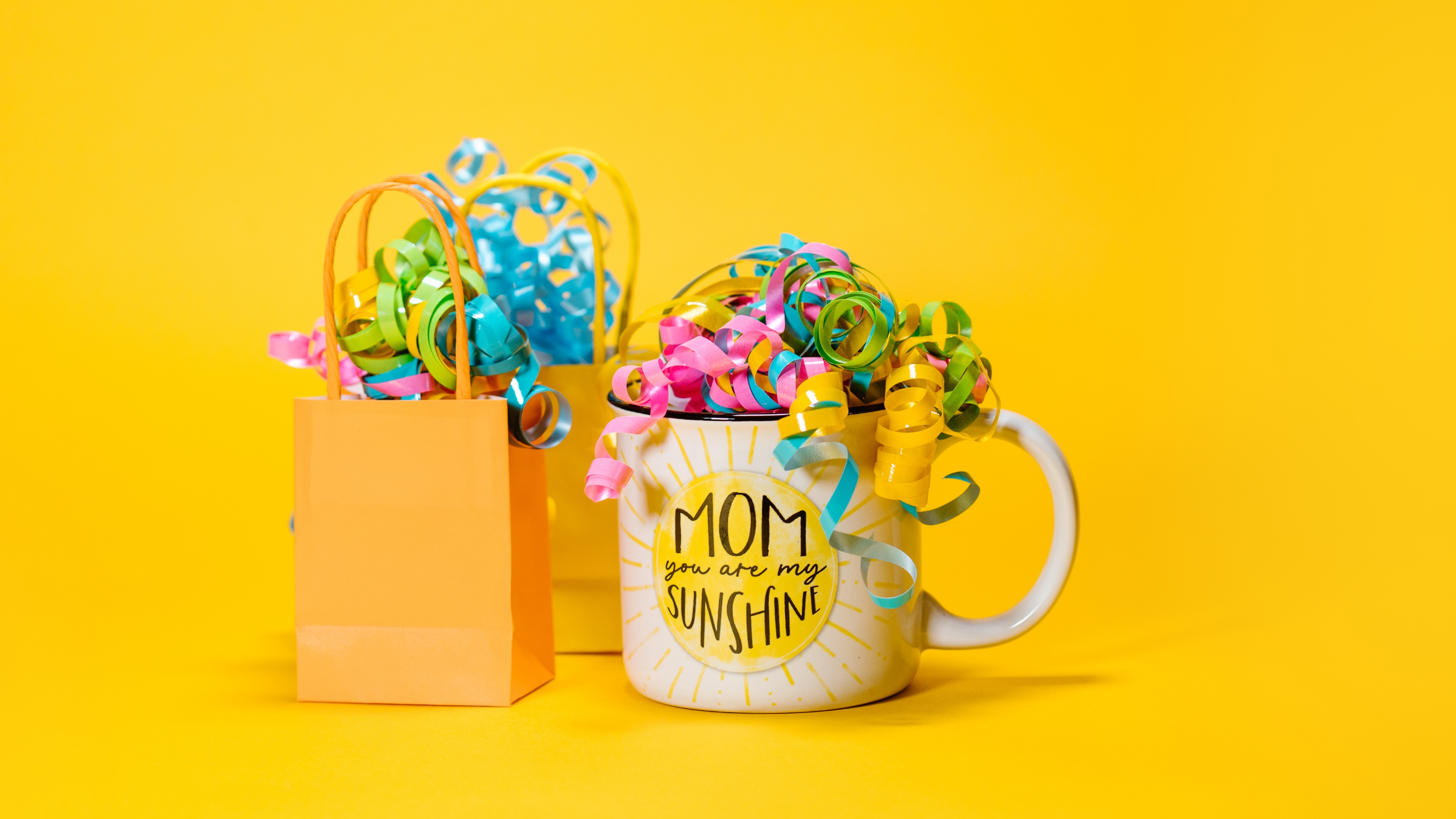 A white mug with the text 'Happy Mother's Day' against a bright yellow background.