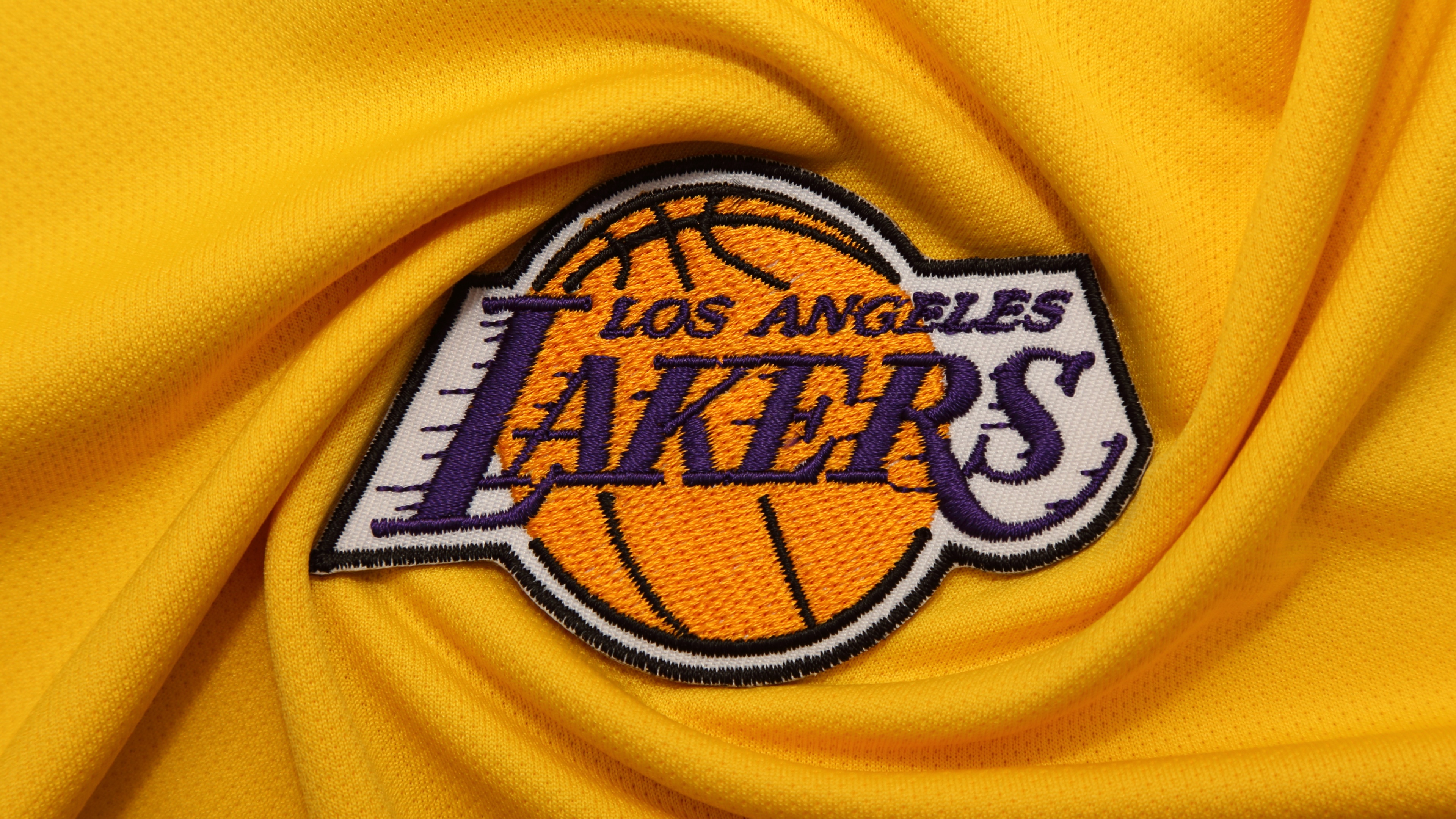 Close-up of a bright yellow football jersey featuring the Los Angeles Lakers logo and premium fabric texture.