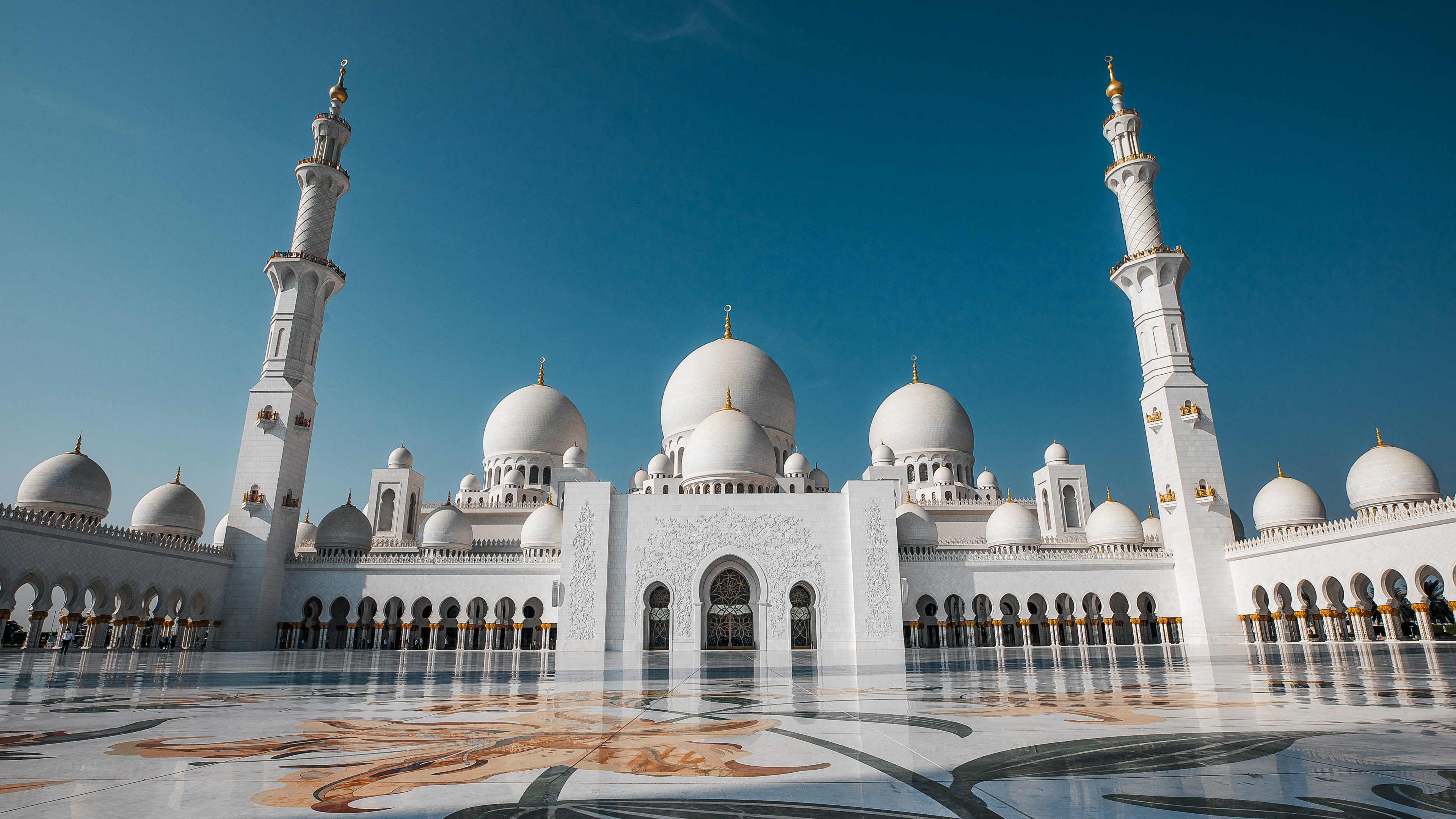 An expansive view of the white marble domes and towering minarets of the Sheikh Zayed Grand Mosque in Abu Dhabi.