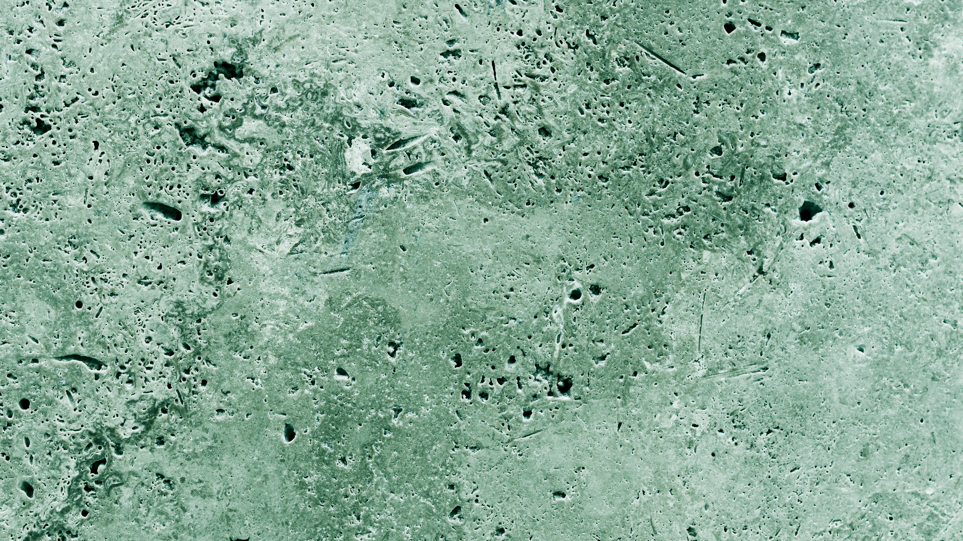 A textured sage green concrete surface with a grainy finish and green backdrop.