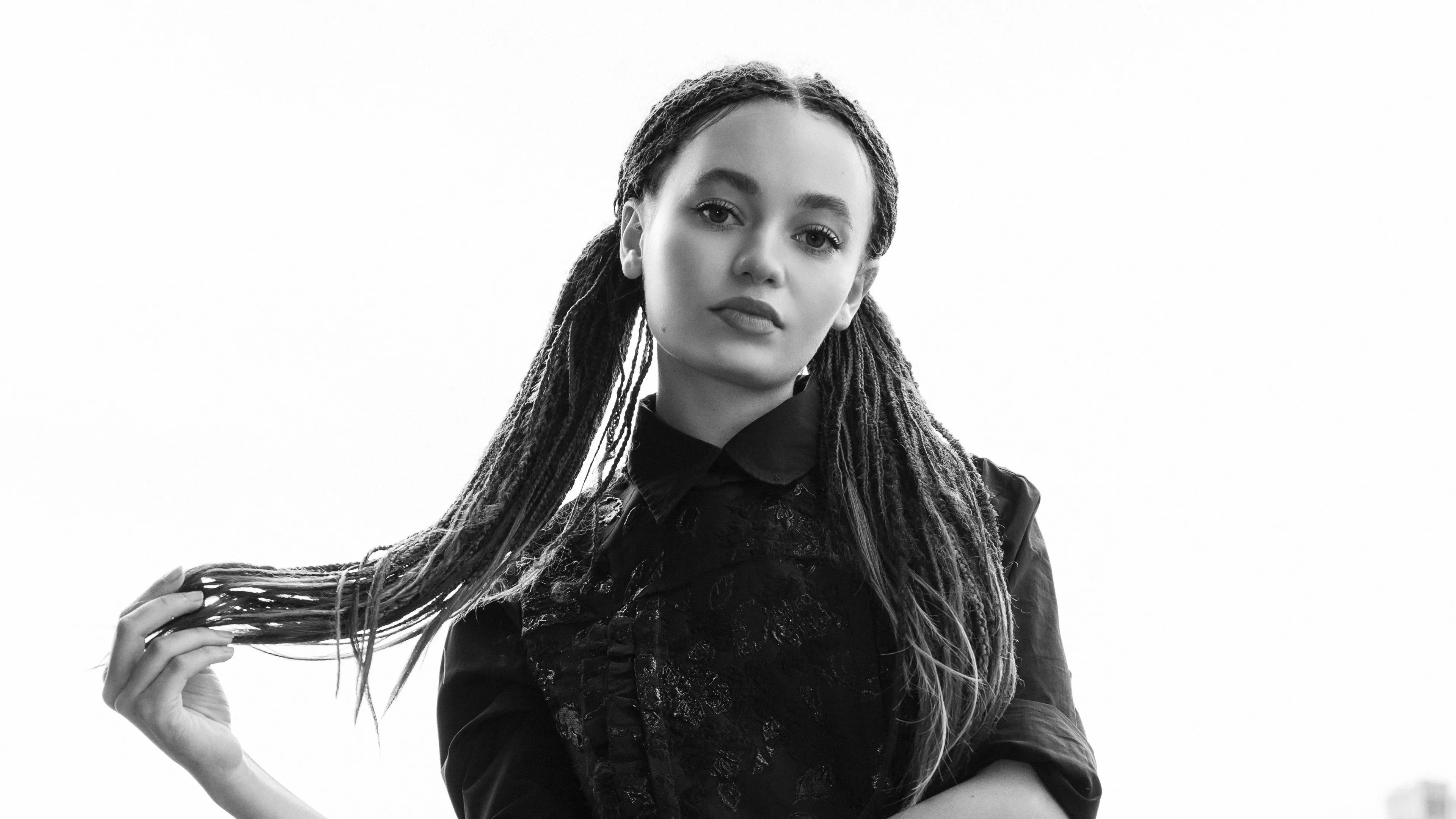 A high-contrast black and white fashion portrait of British actress Nico Parker.
