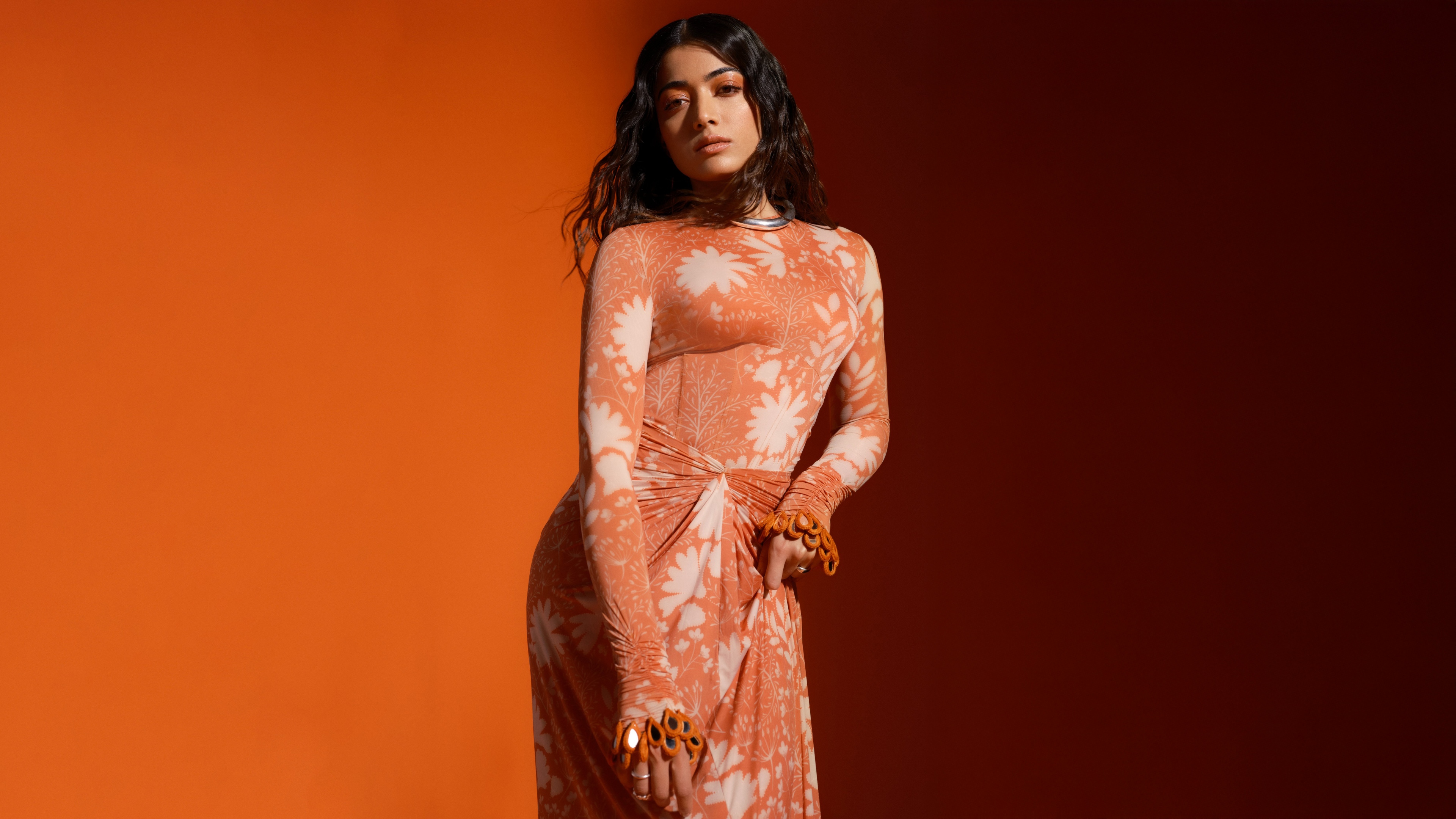Monochromatic orange-themed portrait of Indian actress Rashmika Mandanna.