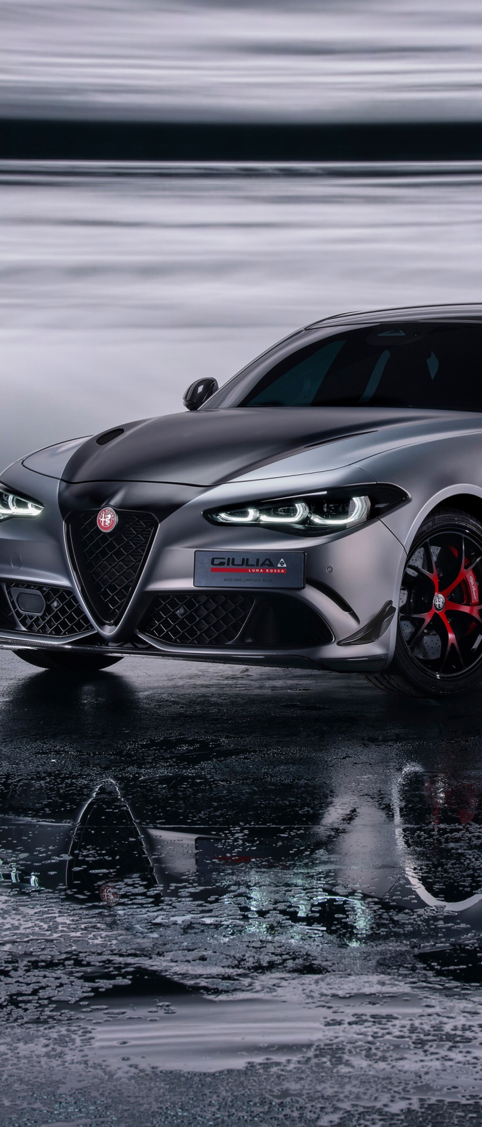 A cinematic, high-detail view of an Alfa Romeo Giulia Quadrifoglio against a dark, moody background, showcasing its sleek metallic curves and luxury automotive design.