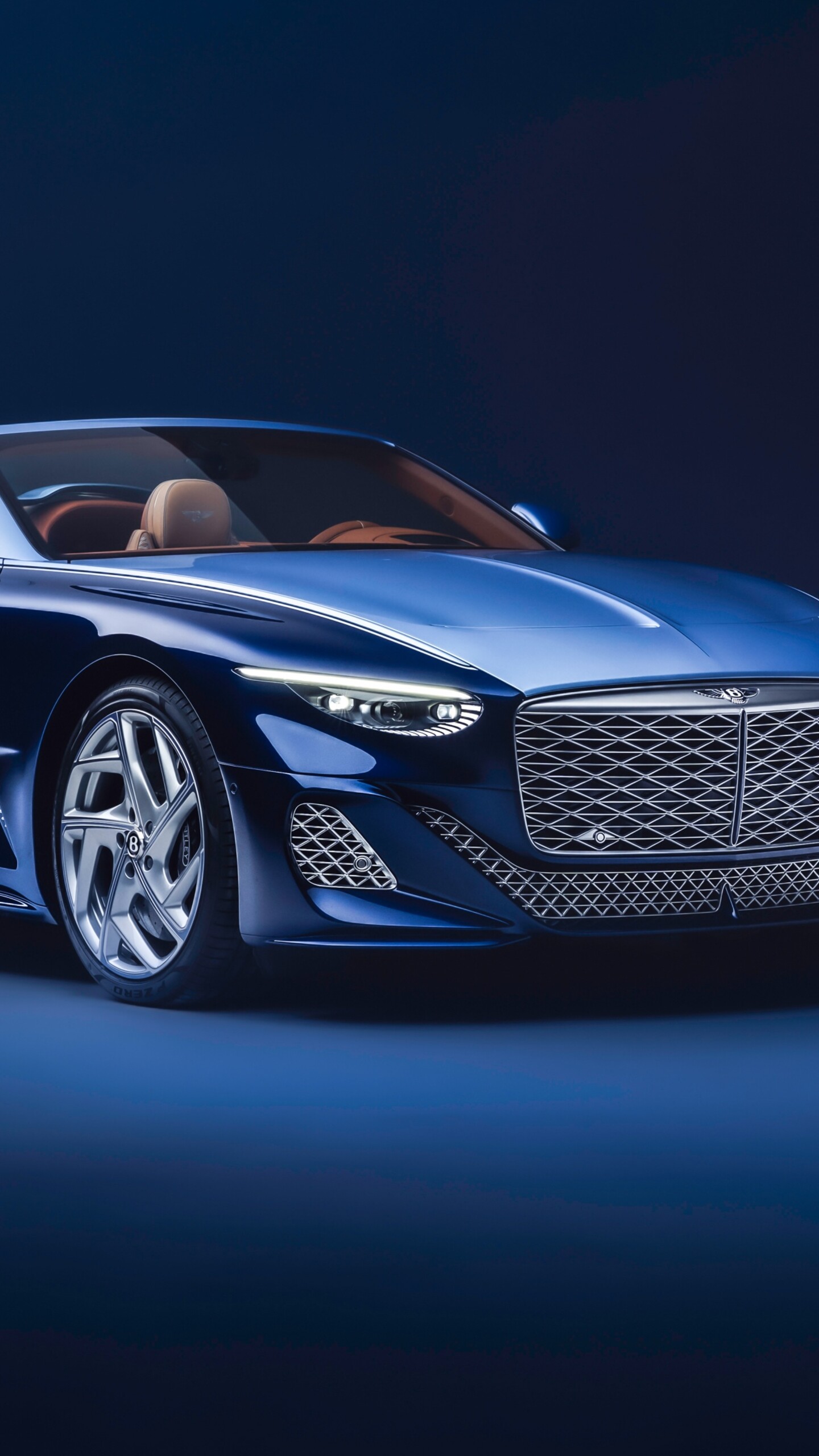 A high-resolution image of a blue Bentley Mulliner Batur Convertible against a deep blue background.