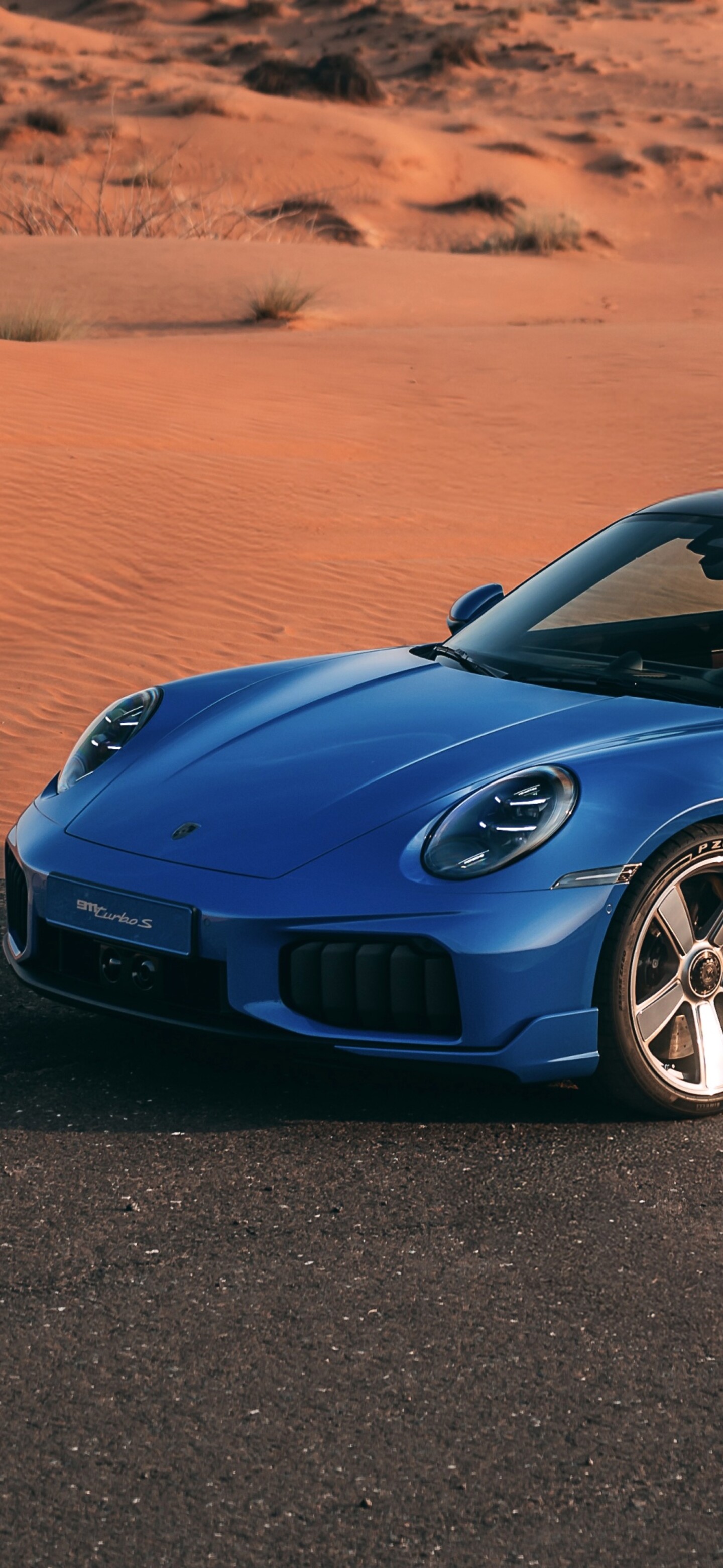 A futuristic 2026 Porsche 911 Turbo S supercar parked on expansive desert sand dunes under bright sunlight.