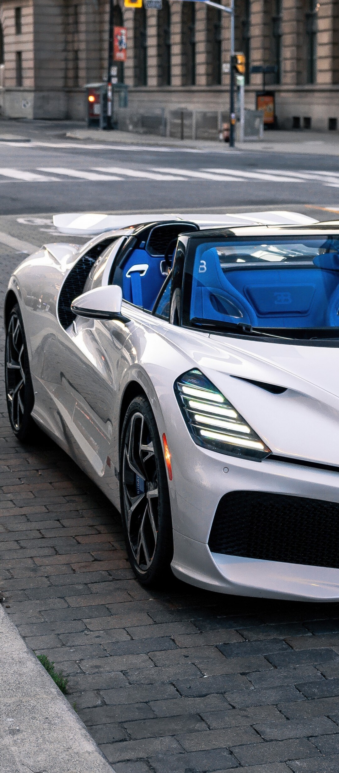 A sleek white Bugatti W16 Mistral hyper sports car driving on a street in Toronto.