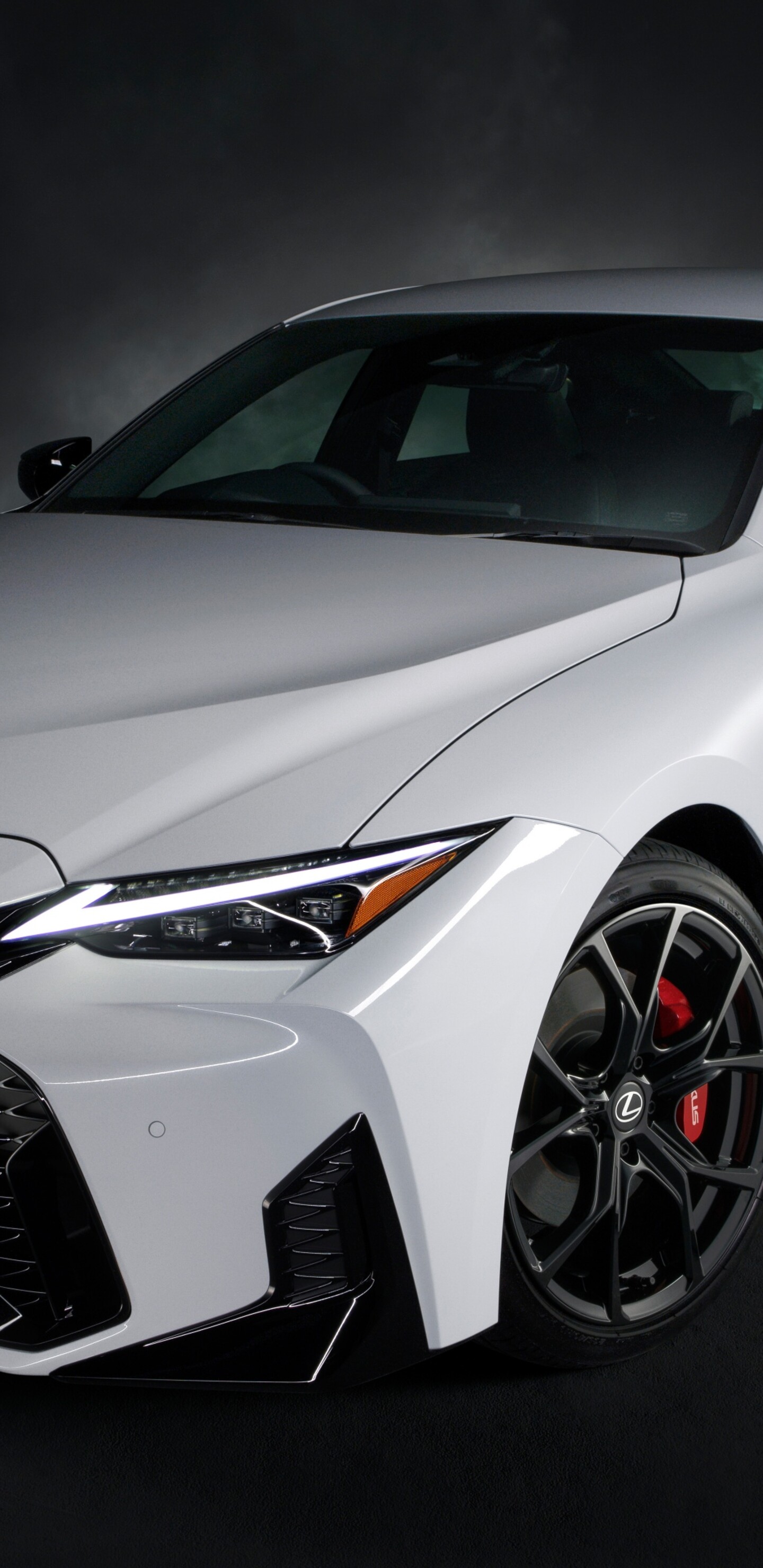 A luxury 2026 Lexus IS 300h sedan presented in a dark, cinematic atmosphere with high-contrast lighting.