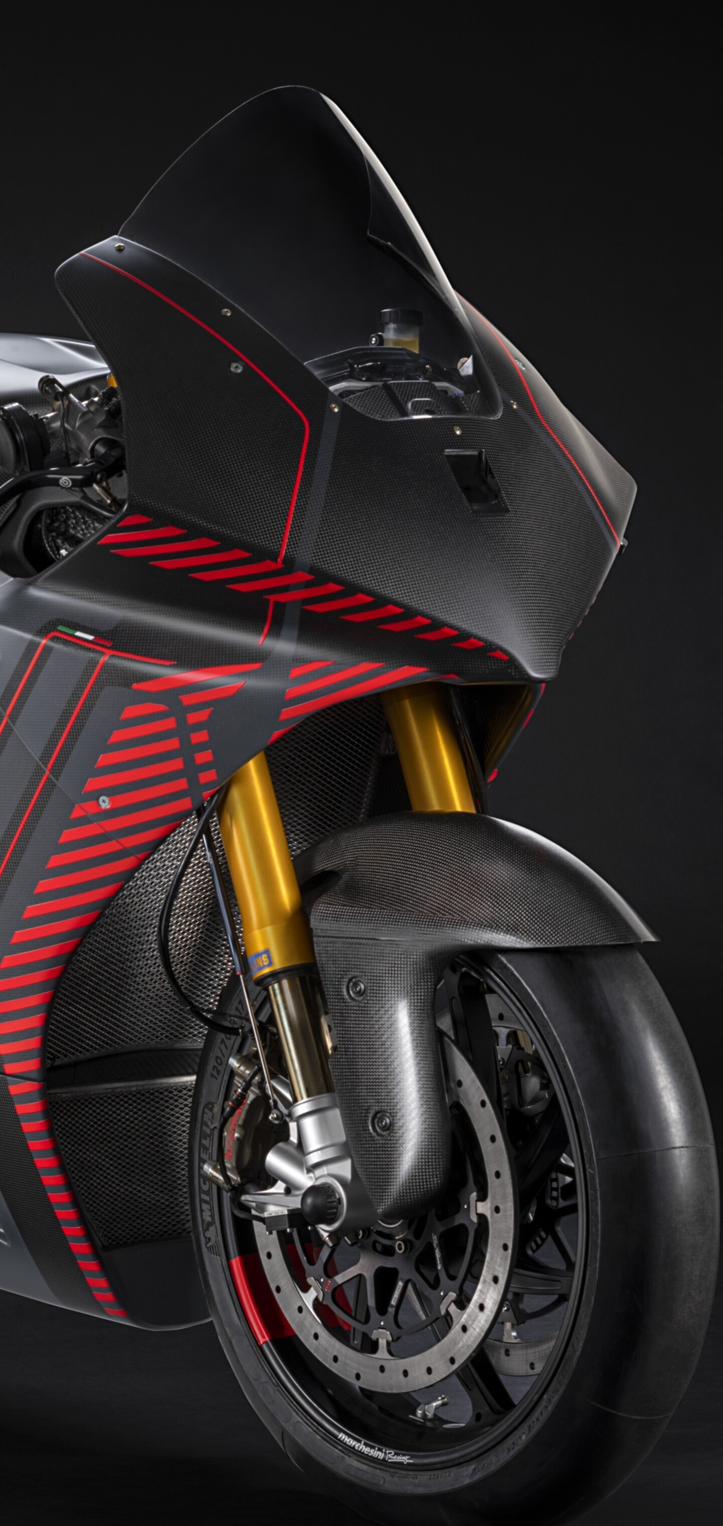A high-detail close-up of a Ducati sports motorcycle with dramatic lighting against a black background.