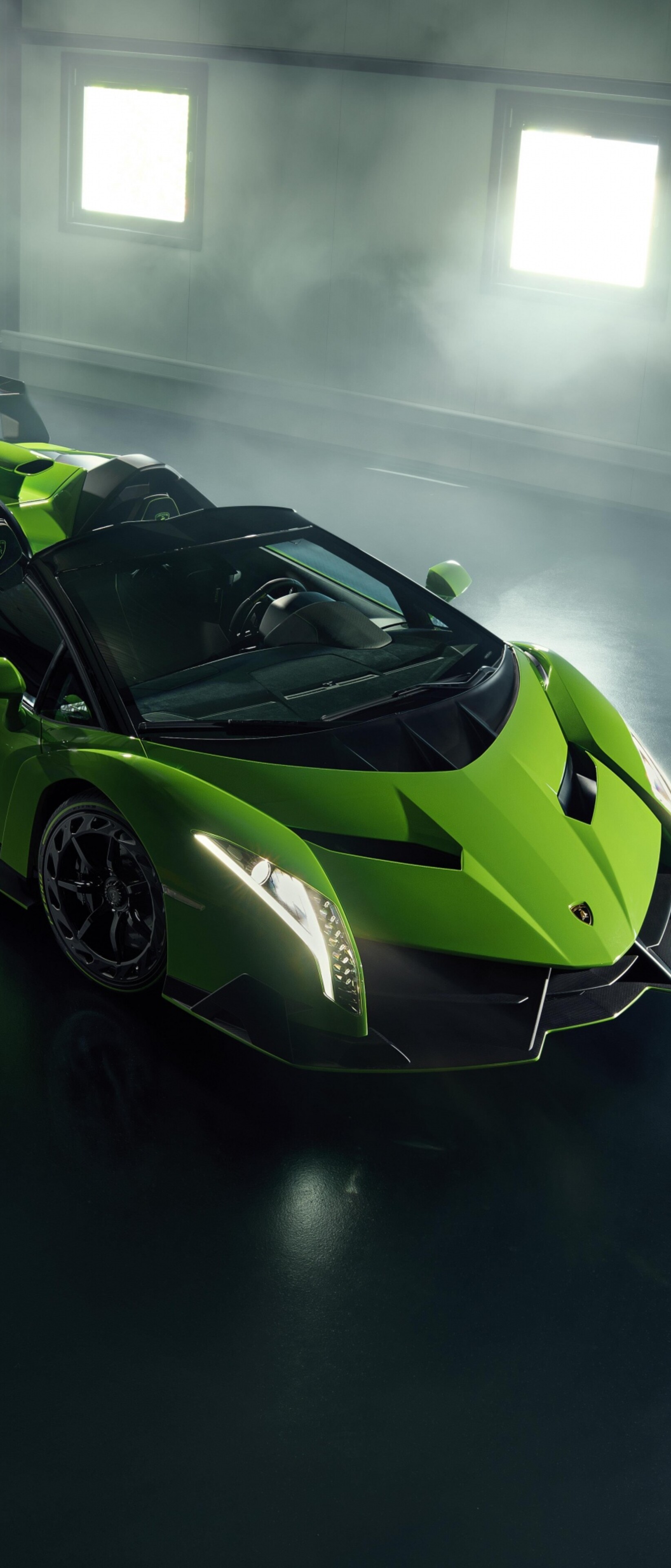 A vibrant green Lamborghini Veneno Roadster parked inside a luxury garage setting.