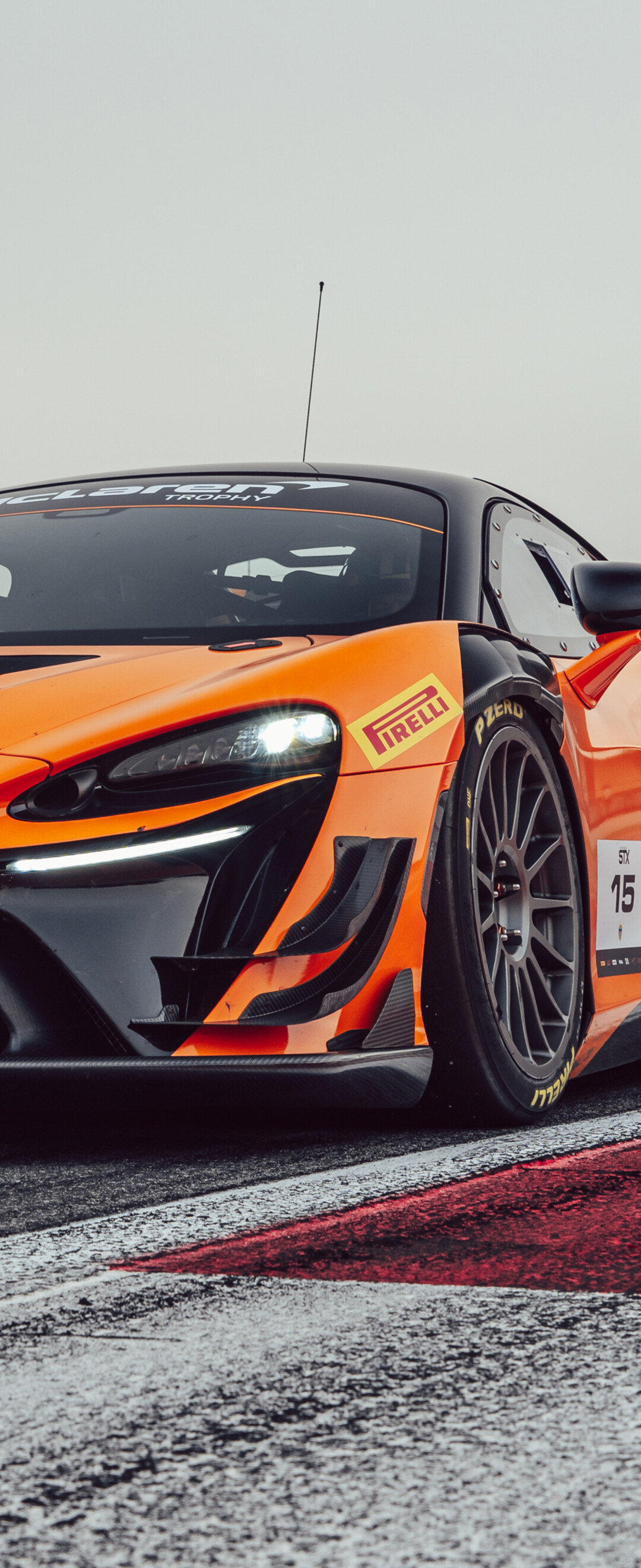 A sleek McLaren Artura race car driving on an asphalt track with a futuristic 2026 design.