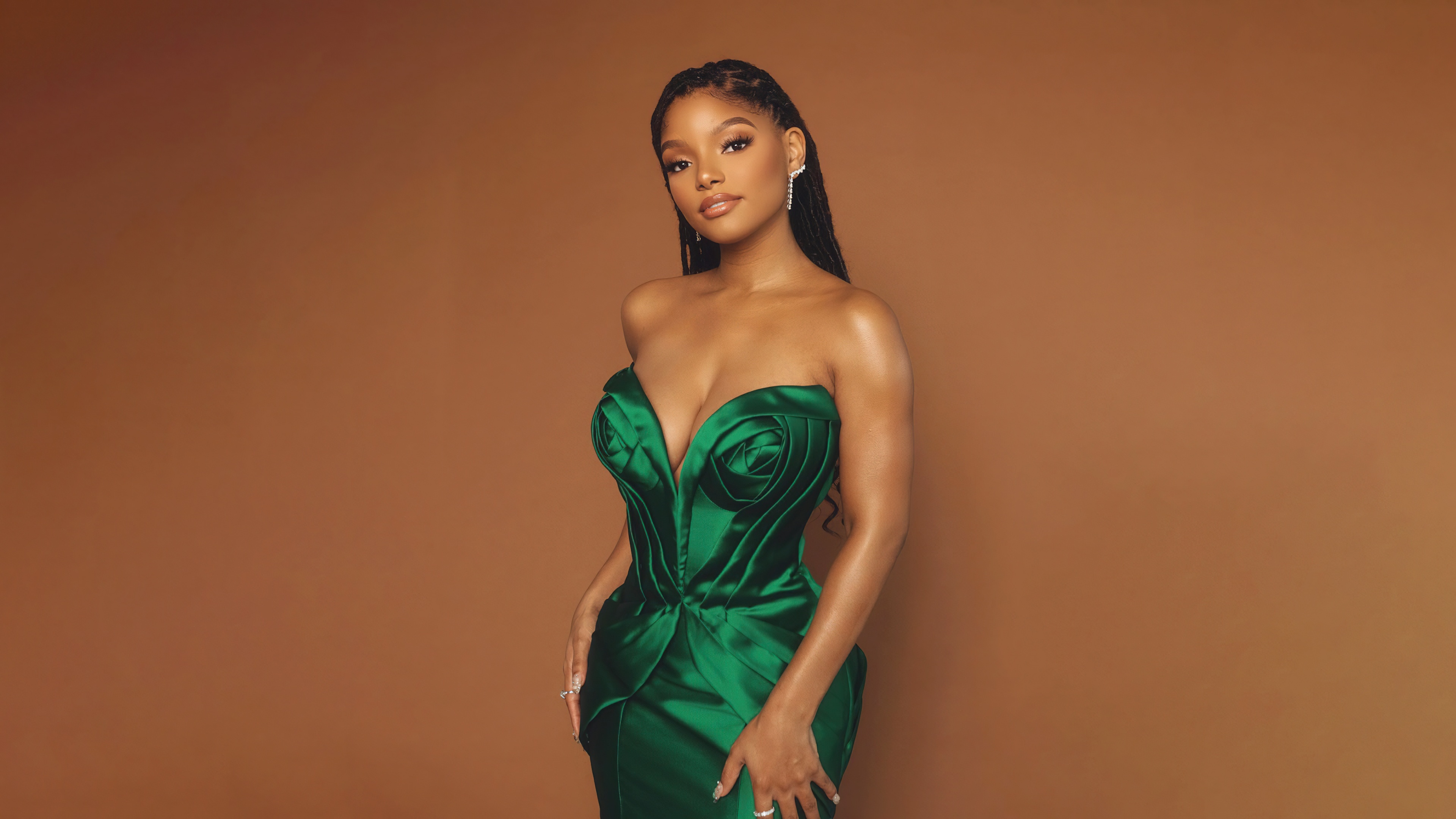 A professional close-up portrait of actress Halle Bailey against a solid brown background.